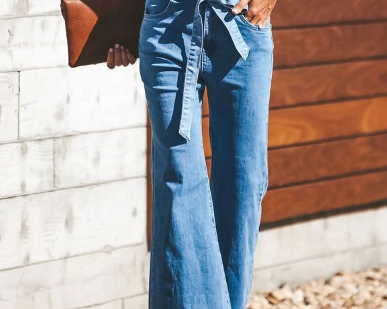 NEWYORKLISTED STYLE COLLECTION: Person wearing blue jeans with a white top, standing against a wooden wall.