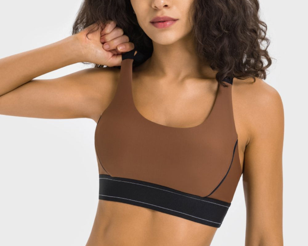 NEWYORKLISTED ACTIVEWEAR COLLECTION: Woman wearing a brown sports bra and leggings with black accents on a white background