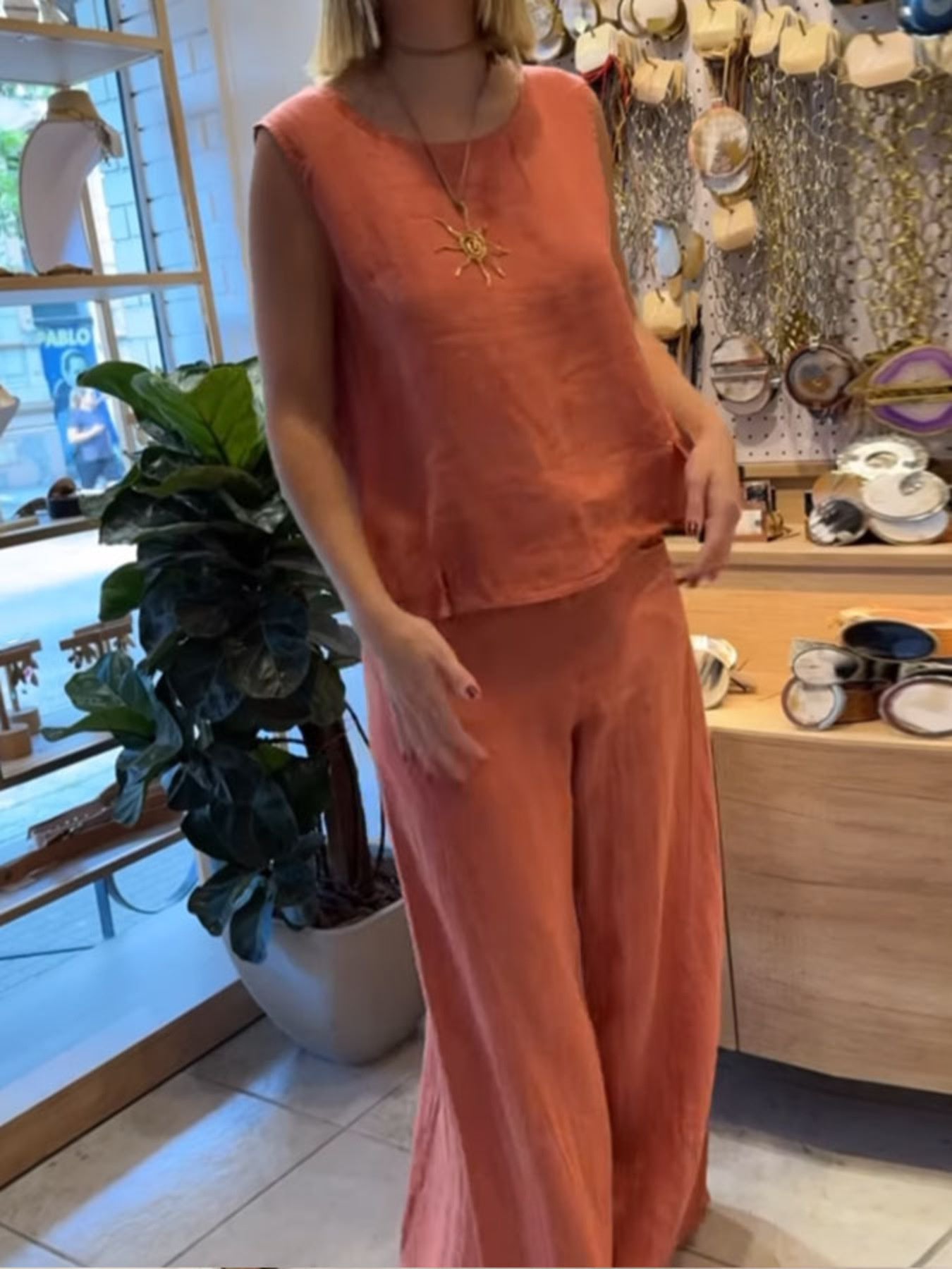NEWYORKLISTED COMFORT COLLECTION: Person wearing an orange outfit in a store setting with decor and plants.