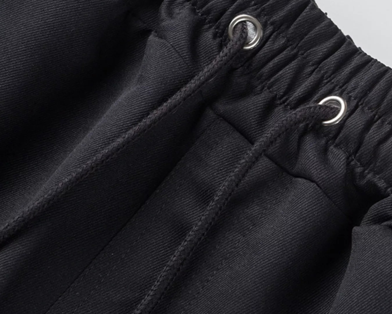 NEWYORKLISTED ATLAS MEN'S COLLECTION: Close-up of black pants with drawstring waistband on a light gray background