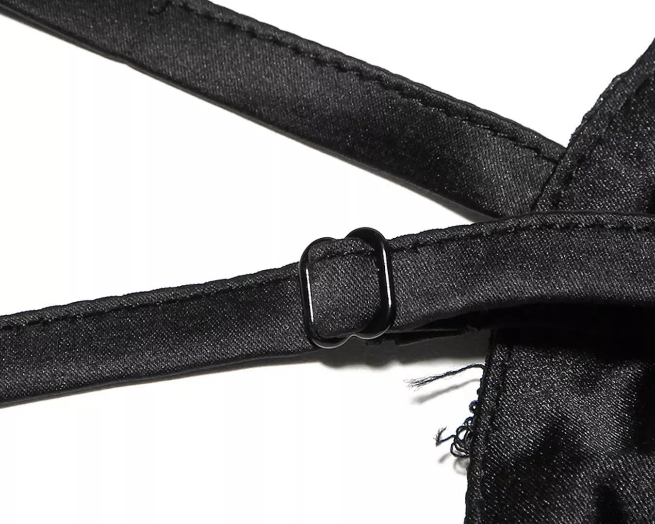 NEWYORKLISTED STYLE COLLECTION: Close-up of a black satin garment with straps on a white background