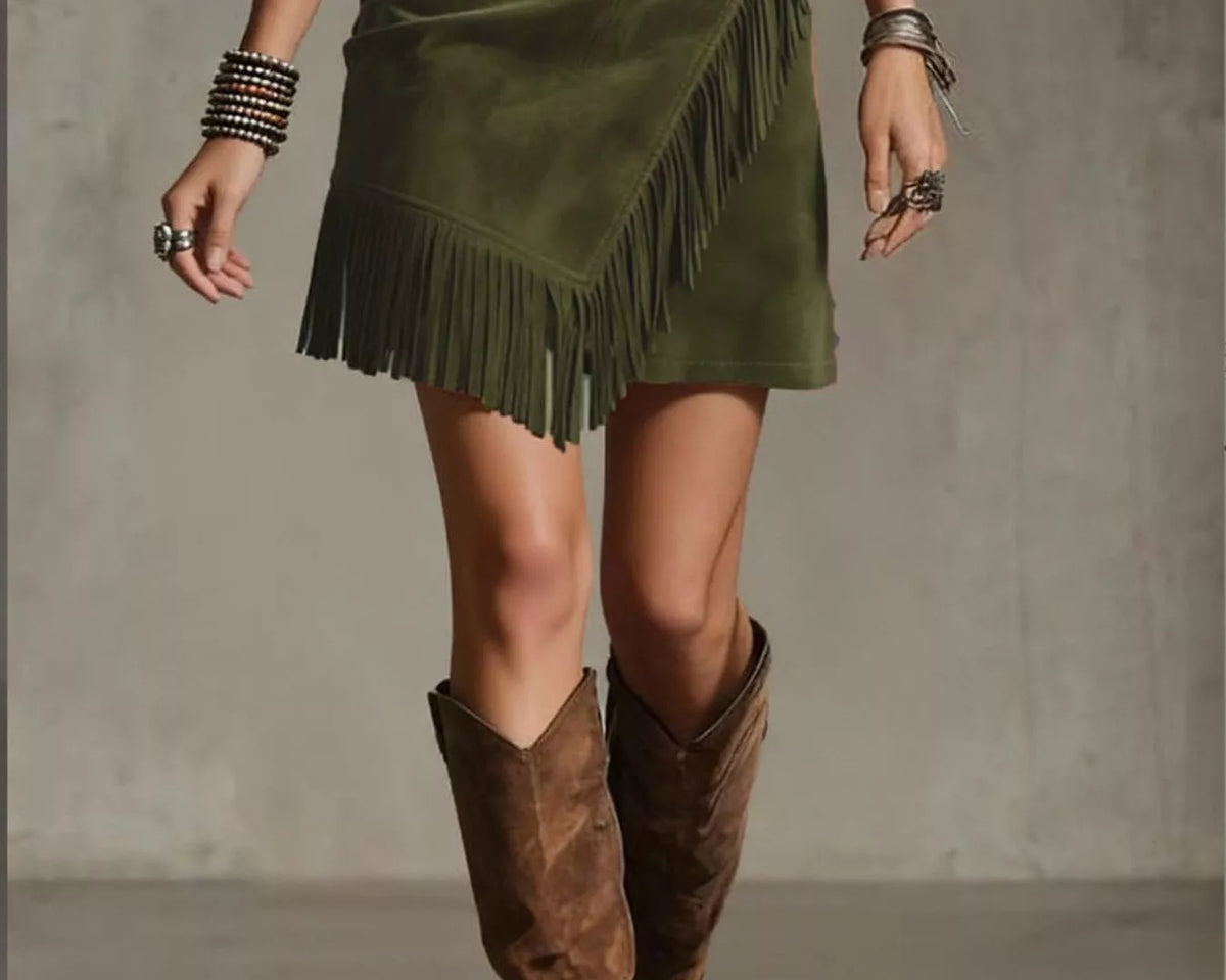 NEWYORKLISTED STYLE COLLECTION: Person wearing a green suede skirt with fringe and brown knee-high boots on a plain background