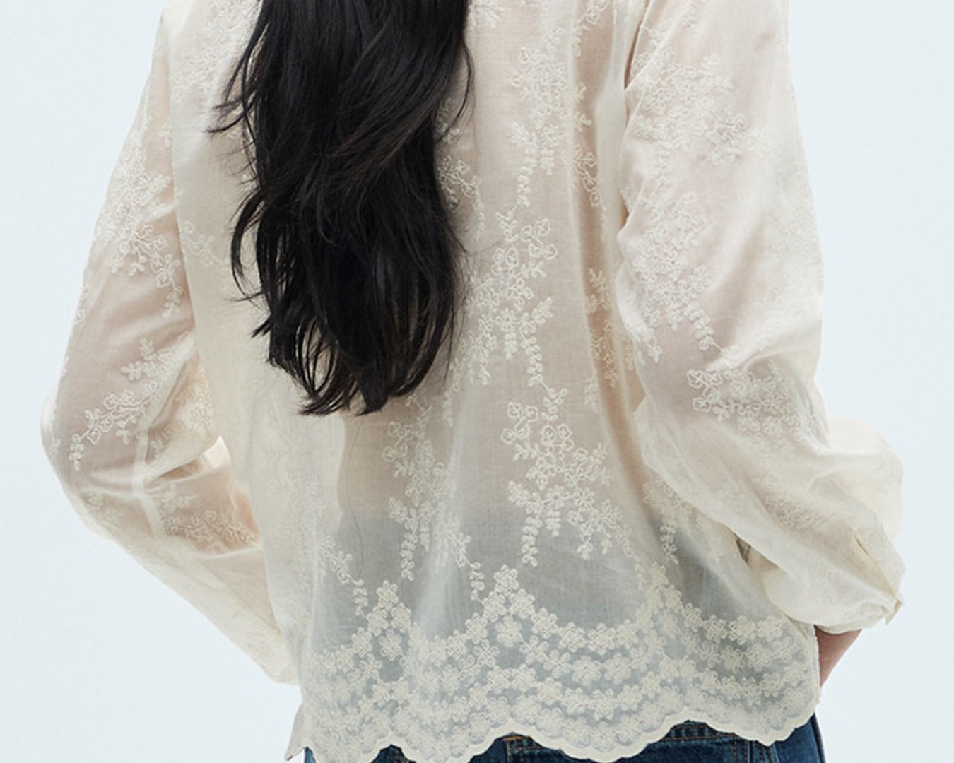 NEWYORKLISTED STYLE COLLECTION: Person wearing a white lace blouse and blue jeans on a light gray background