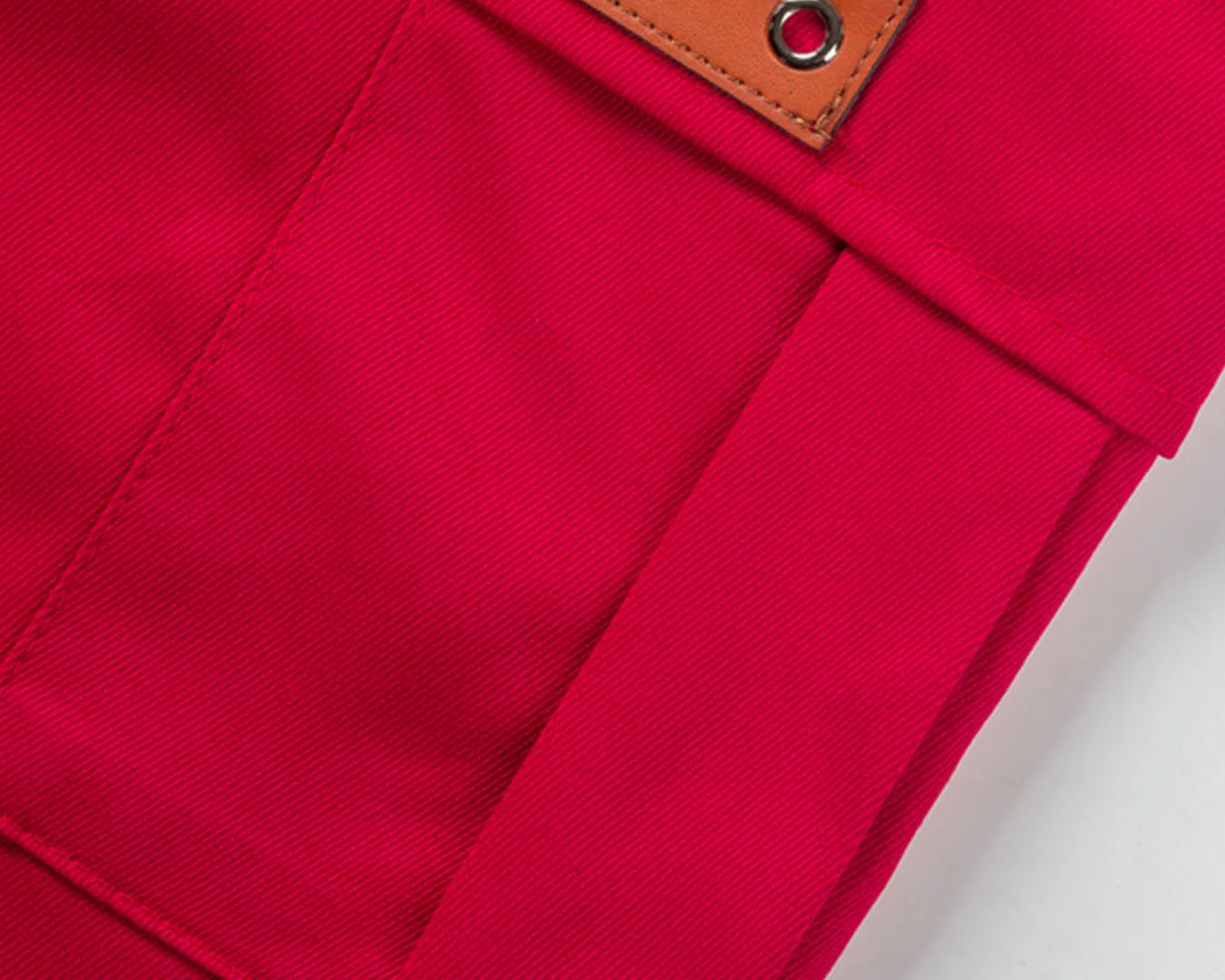 NEWYORKLISTED ATLAS MEN'S COLLECTION: Close-up of a red fabric pocket with a brown leather patch on a white background