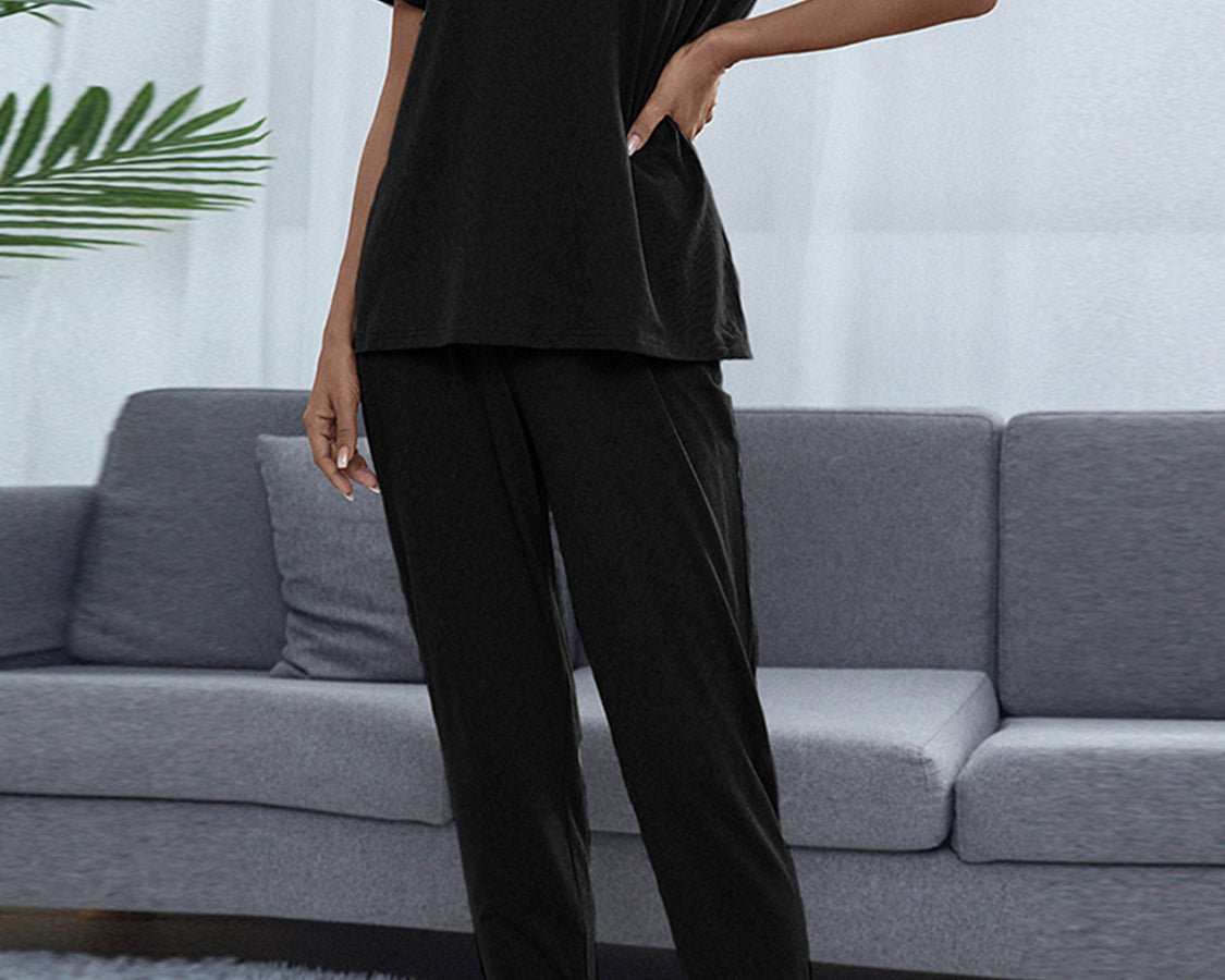NEWYORKLISTED Intimate Apparel: Person wearing a black outfit standing in a living room with a gray sofa and white walls.