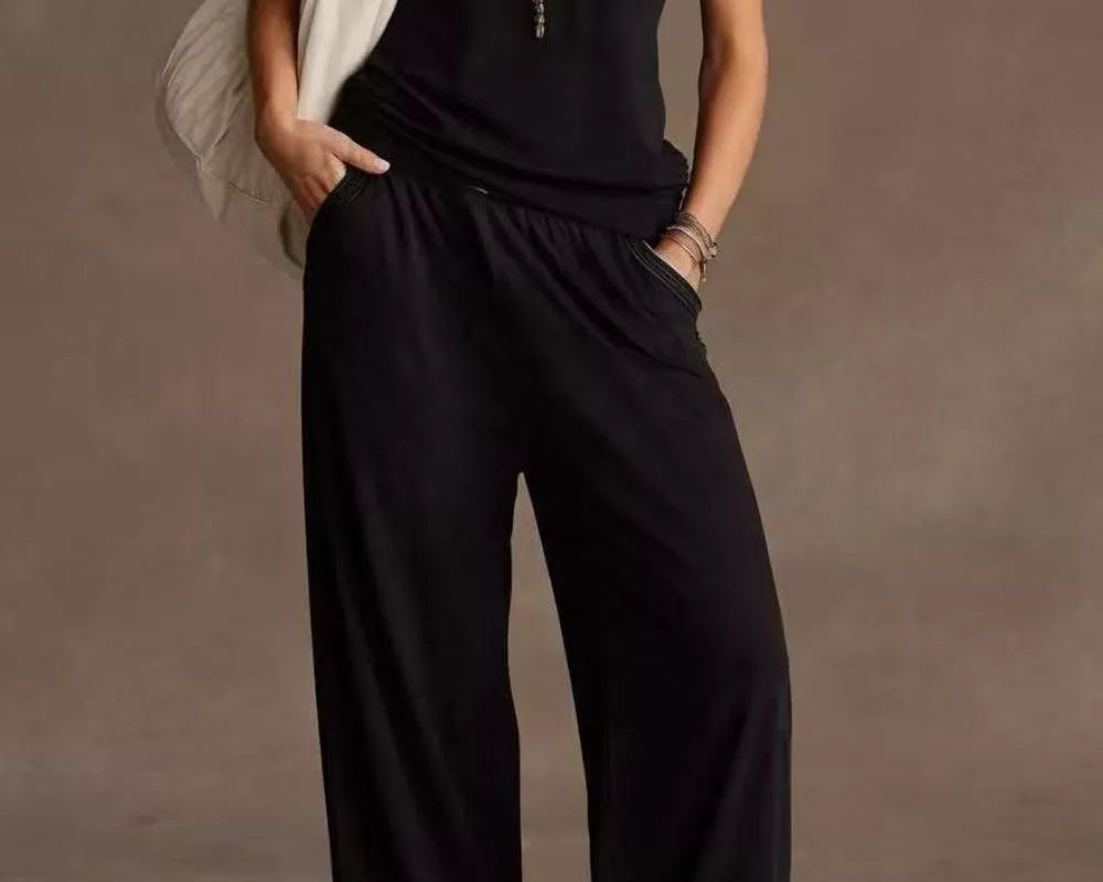 NEWYORKLISTED STYLE COLLECTION: Person wearing a black jumpsuit with a plain background