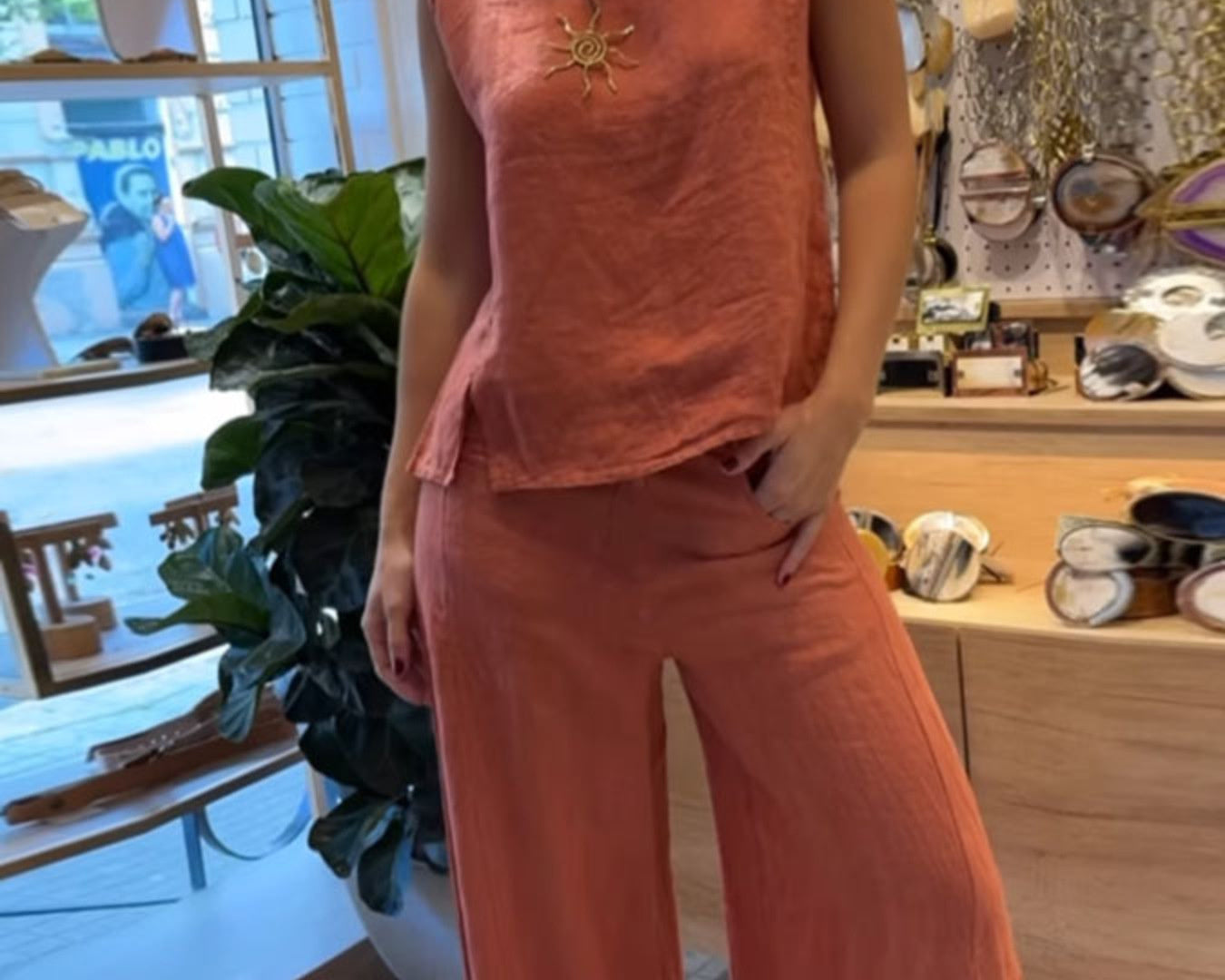 NEWYORKLISTED COMFORT COLLECTION: Person wearing a coral sleeveless top and pants in a store setting.