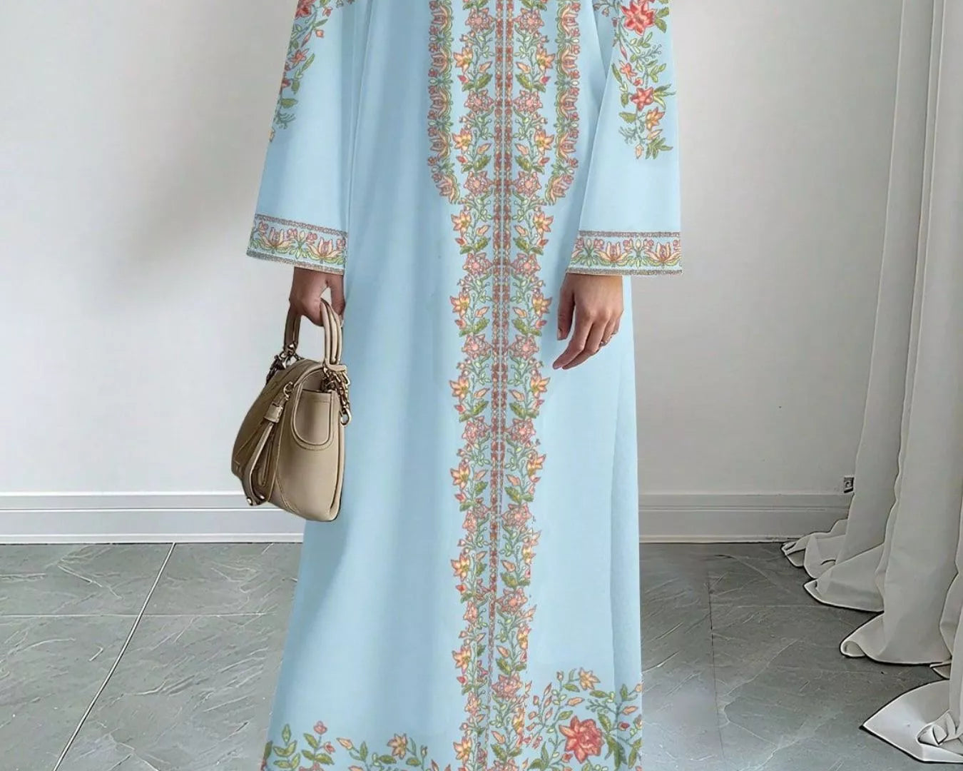 NEWYORKLISTED STYLE COLLECTION: Woman wearing a light blue dress with floral embroidery in a minimal indoor setting.