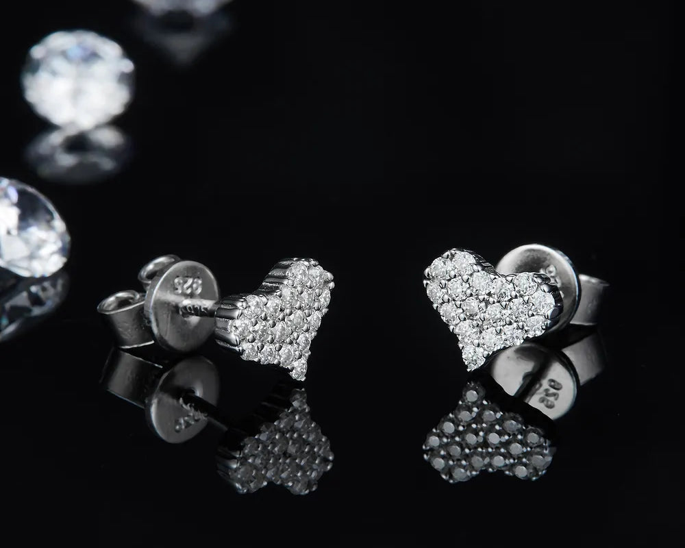 NYLD Glamour Collection By NEWYORKLISTED: Heart-shaped earrings with clear stones on a black background