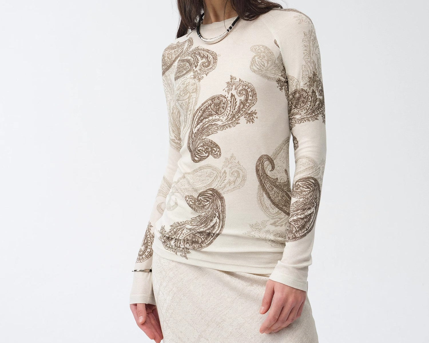 Woman wearing a long-sleeve top with paisley patterns on a white background