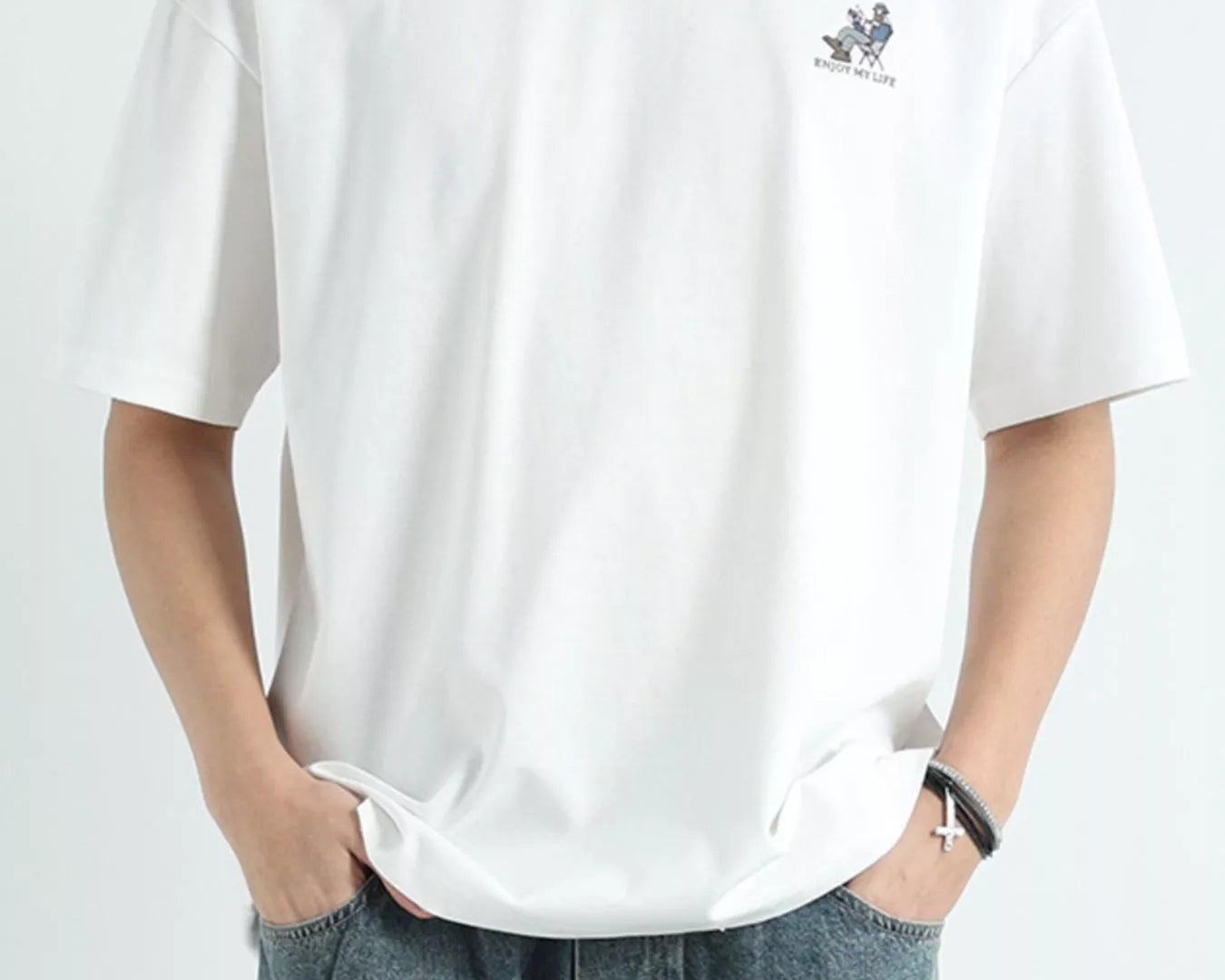 Person wearing a white t-shirt with a small logo on a plain background