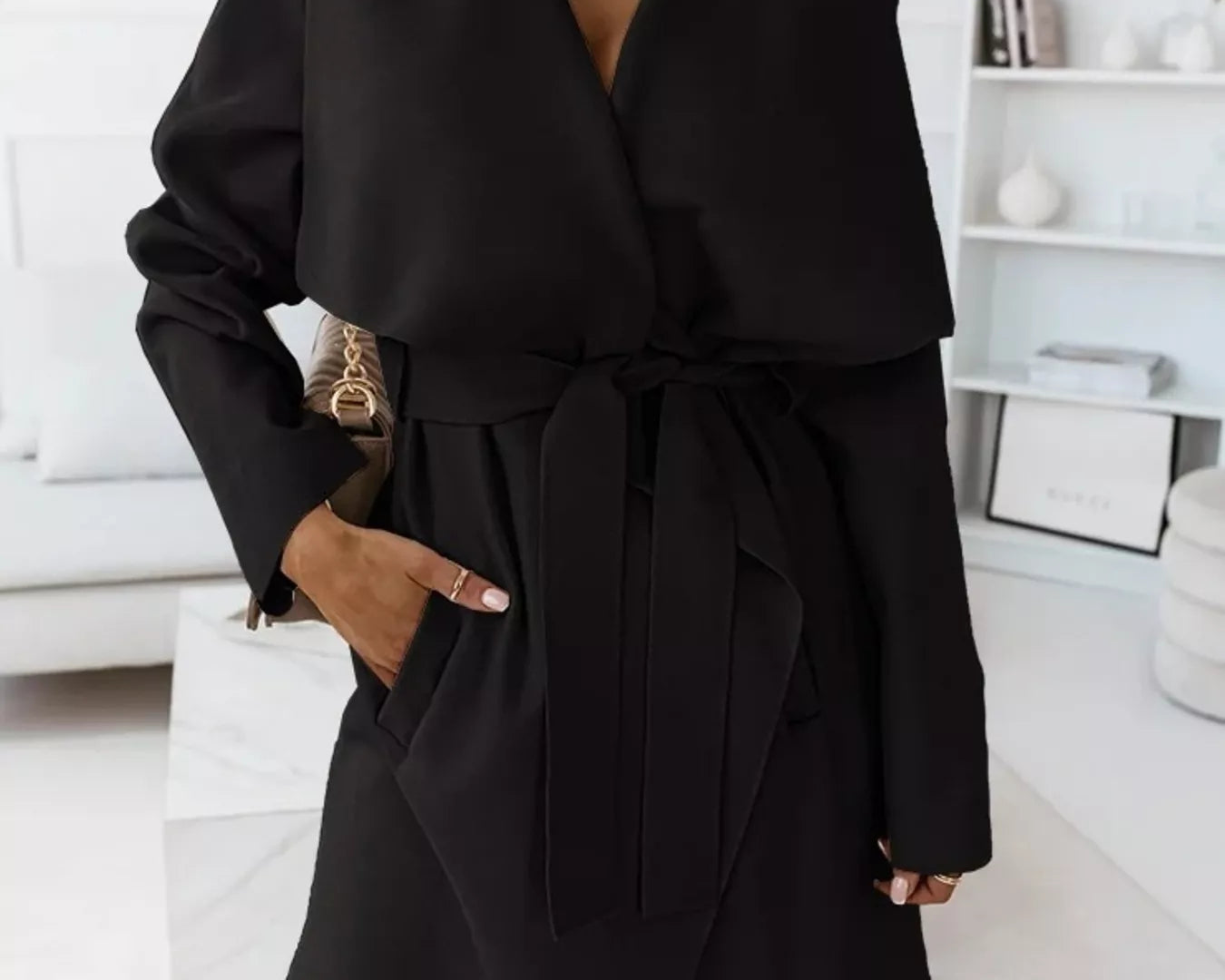 NEWYORKLISTED STYLE COLLECTIONB: Person wearing a black coat in a minimalistic room