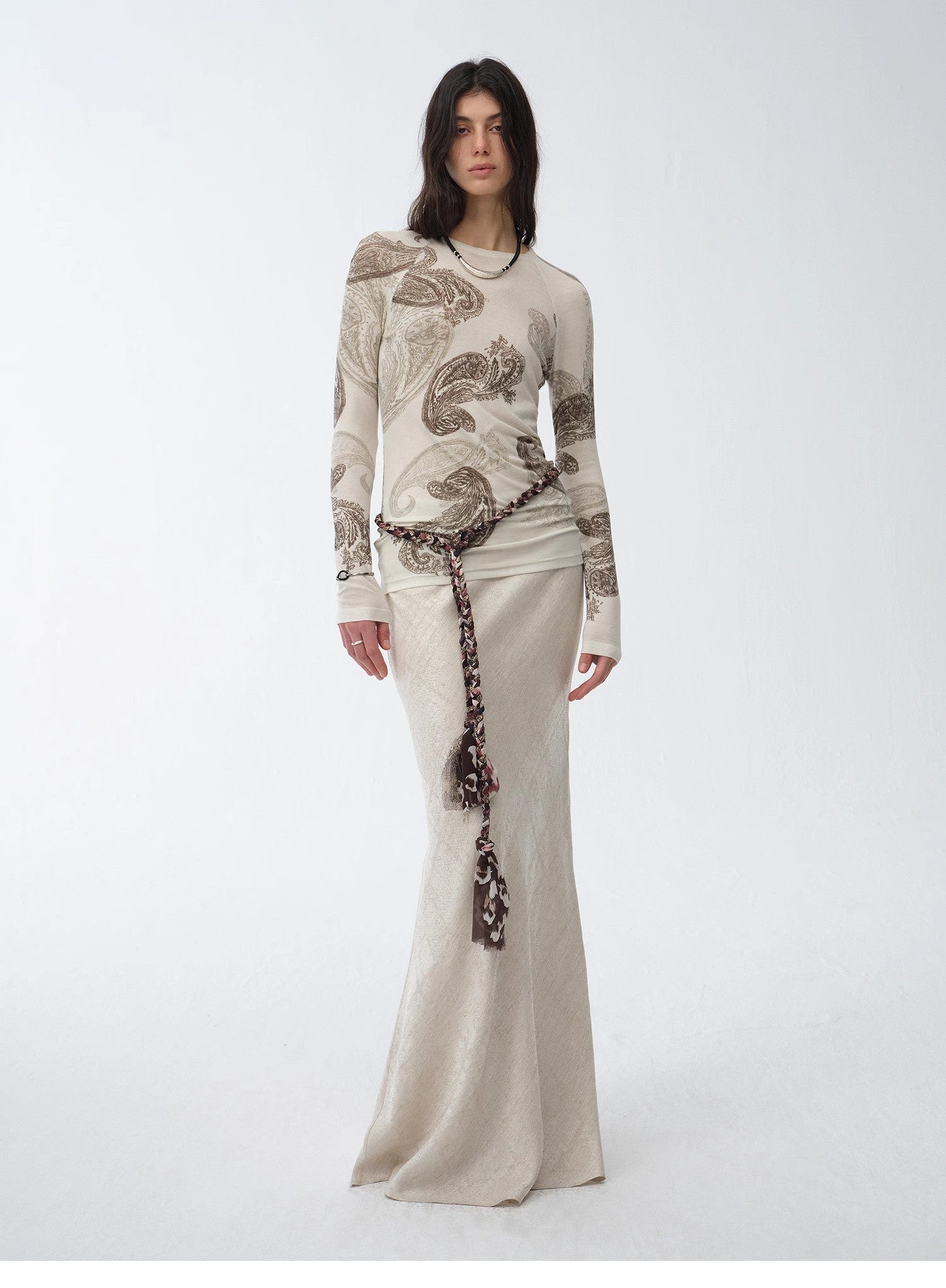 NEWYORKLISTES STYLE COLLECTION: Woman wearing a long, elegant dress with intricate patterns on a white background