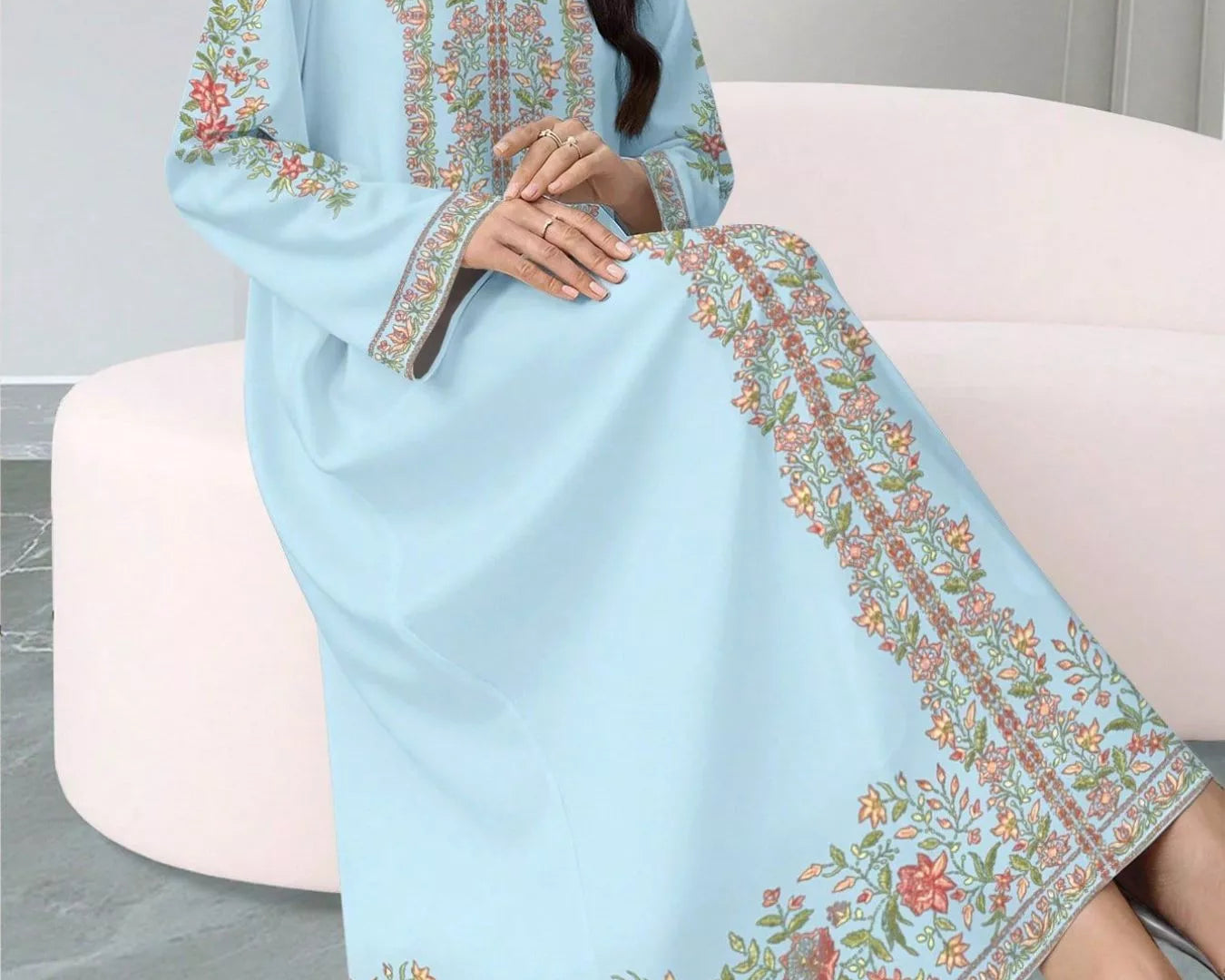 NEWYORKLISTED STYLE COLLECTION: Woman wearing a light blue embroidered dress sitting on a white chair.