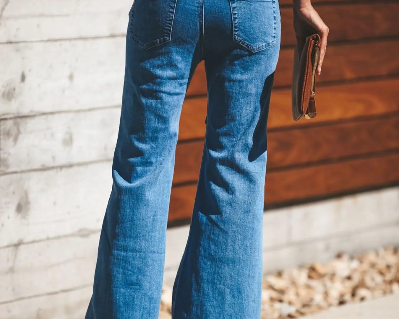 NEWYORKLISTED STYLE COLLECTION: Person wearing blue jeans standing against a wooden wall.