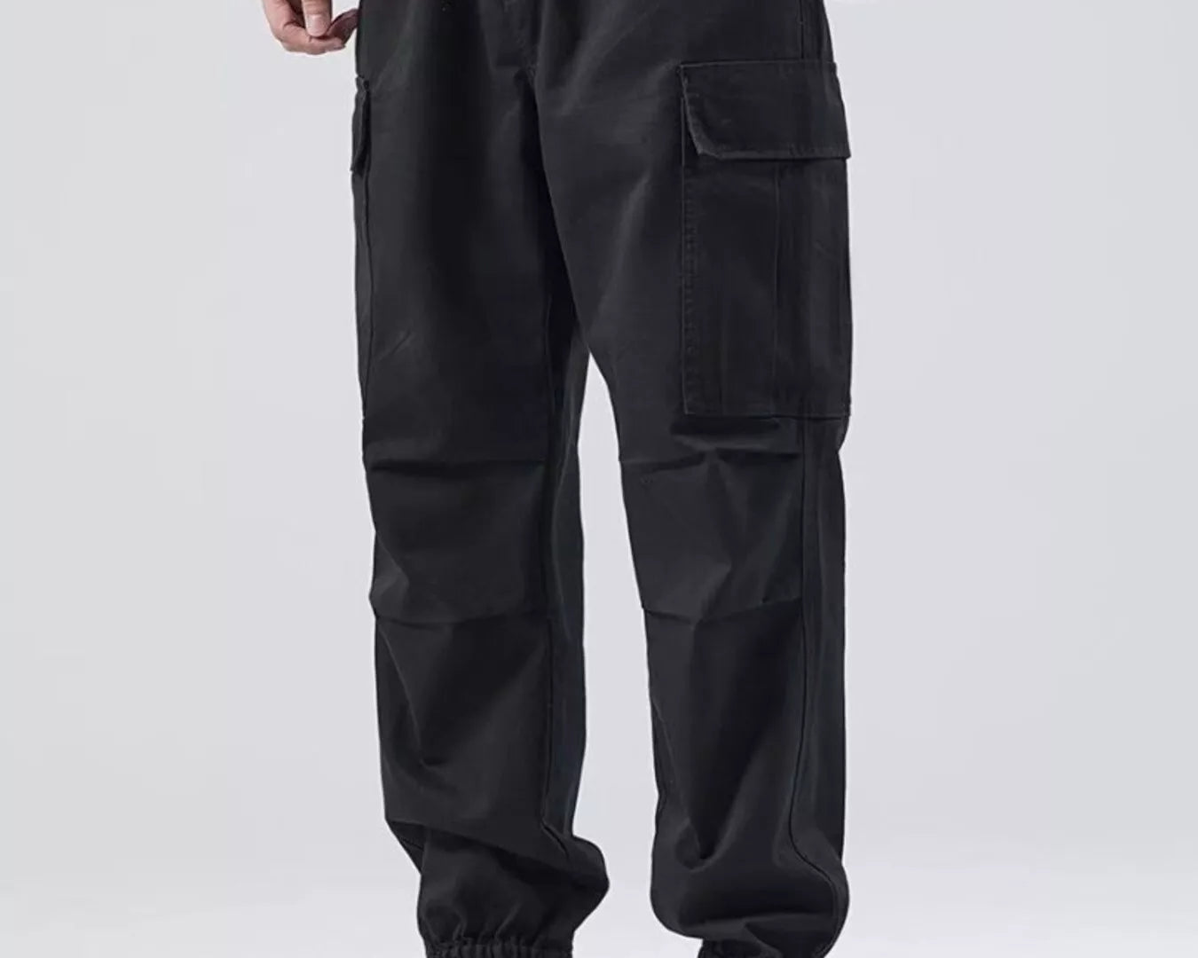 NEWYORKLISTED ATLAS MEN'S COLLECTION: Person wearing black cargo pants and beige boots on a white background