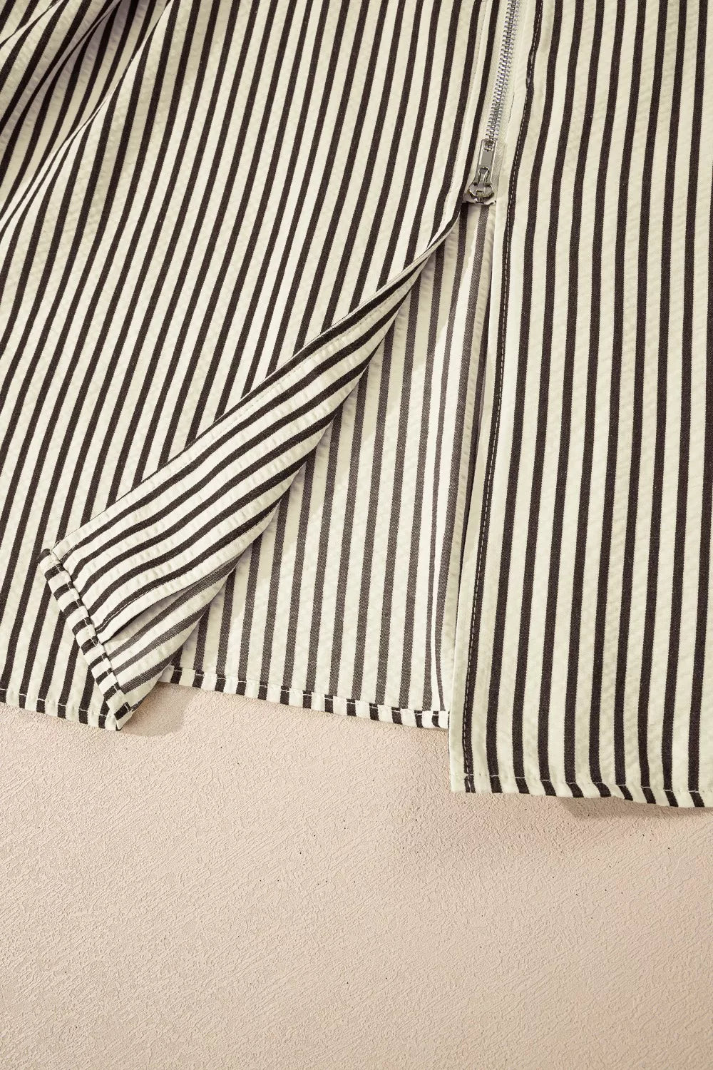 NEWYORKLISTED STYLE COLLECTION: Close-up of a black and white striped shirt on a beige background