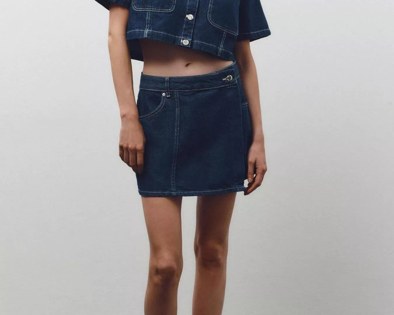 NEWYORKLISTED STYLE COLLECTION: Person wearing a dark denim jacket and skirt set against a plain background