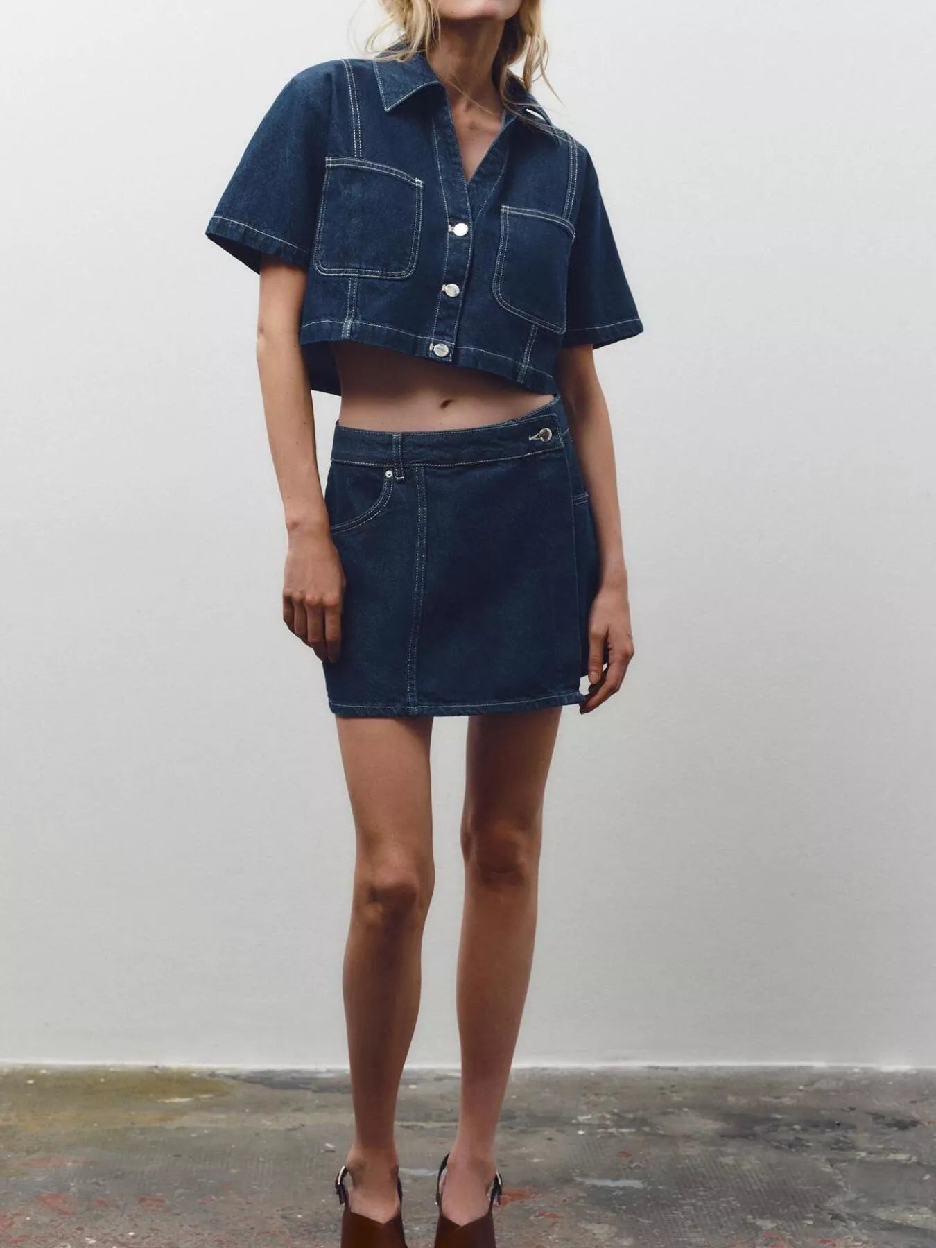 NEWYORKLISTED STYLE COLLECTION: Person wearing a dark denim jacket and skirt set against a plain background