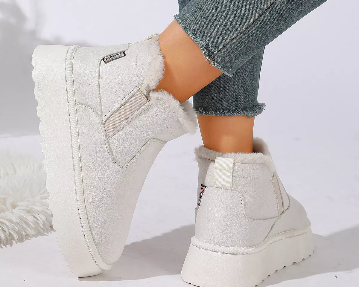 NEWYORKLISTED SHOE COLLECTION: White platform ankle boots with faux fur lining, shown on a model wearing blue jeans against a white studio background.