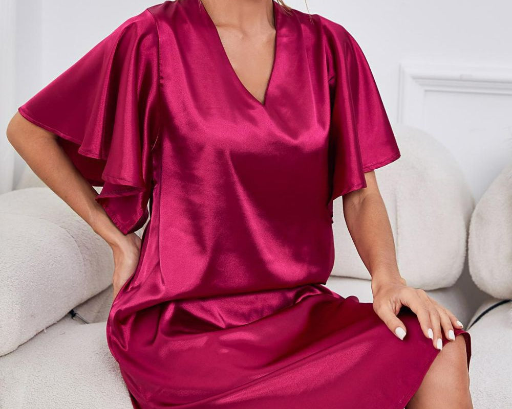 NEWYORKLISTED Intimate Apparel: Woman wearing a vibrant pink satin dress sitting on a white couch.