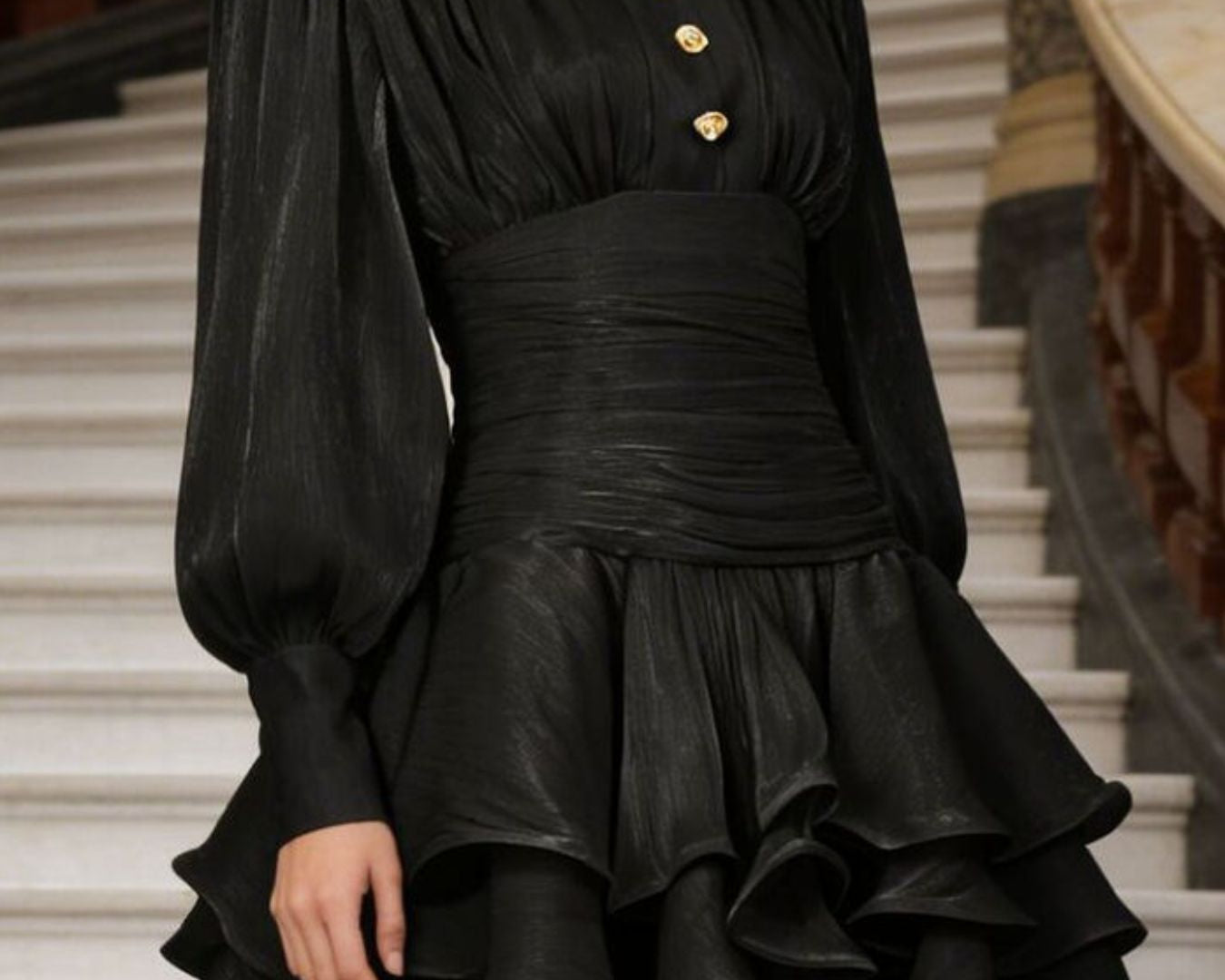 NEWYORKLISTED STYLE COLLECTION: Black dress with gold buttons worn by a person on a staircase