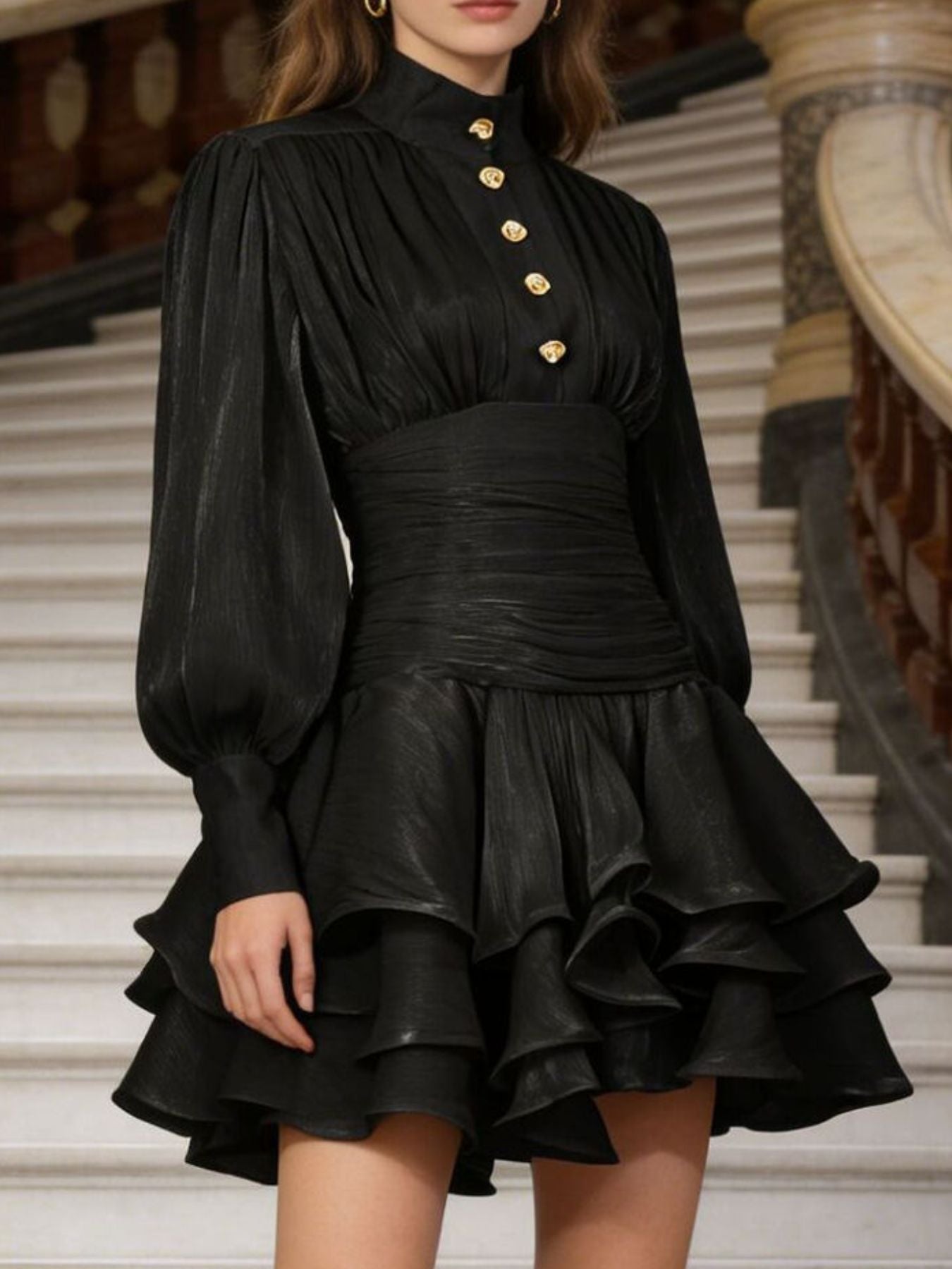 NEWYORKLISTED STYLE COLLECTION: Black dress with gold buttons worn by a person on a staircase