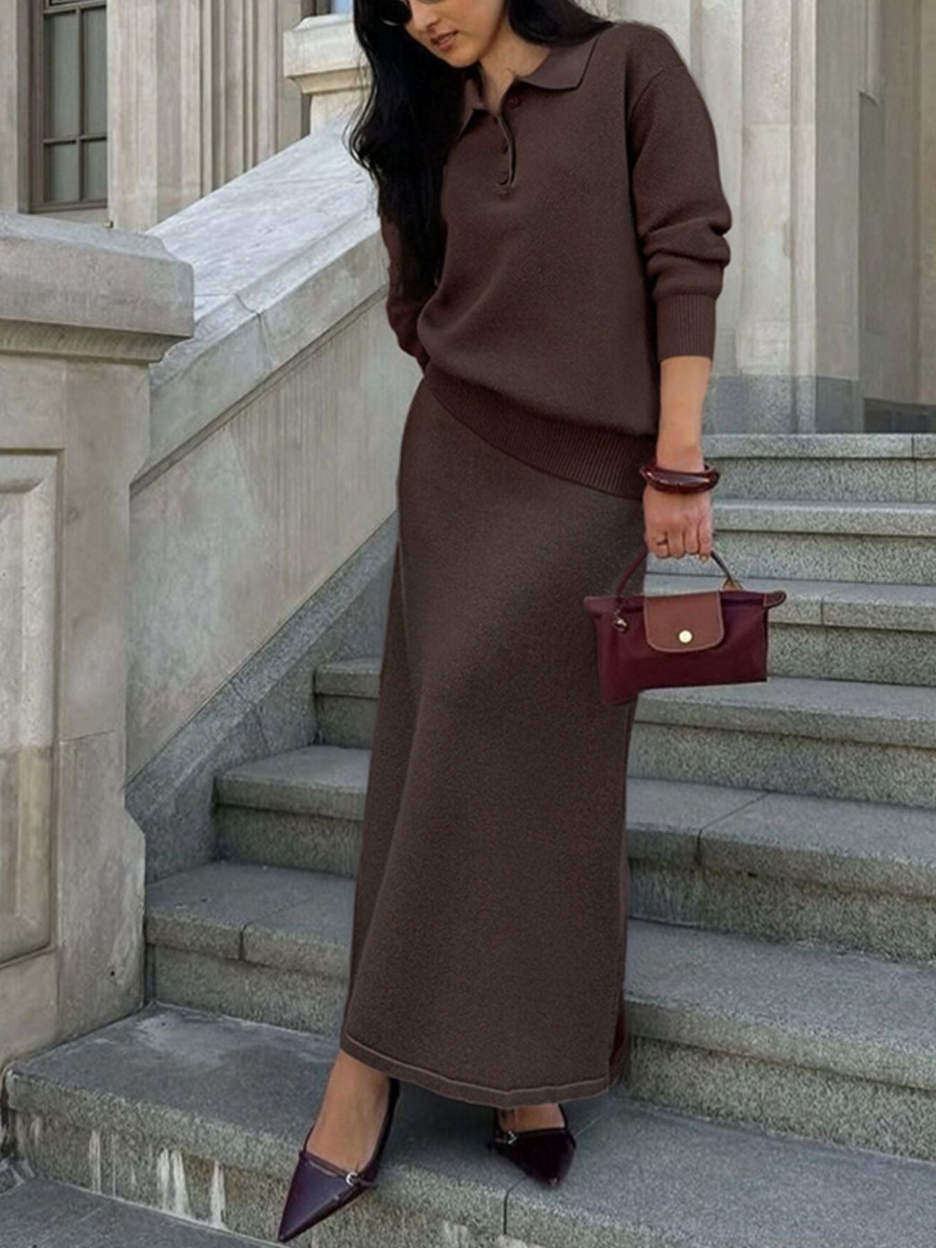 NEWYORKLISTED Comfort Collection: Woman in brown outfit with red handbag standing on stone steps.