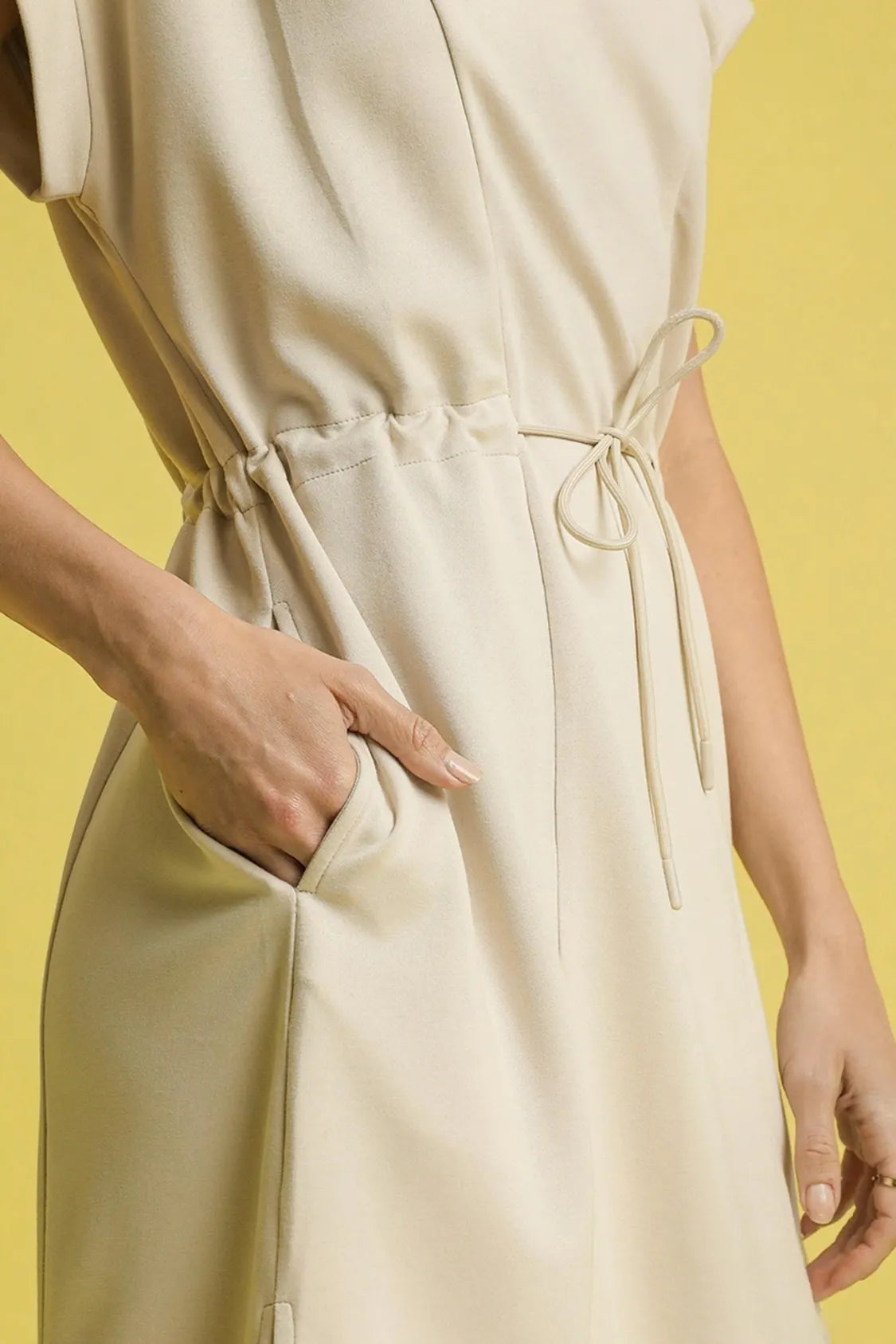 NEWYORKLISTED STYLE COLLECTION: Short Sleeve Midi Tee Dress Beige jumpsuit worn by a person on a yellow background