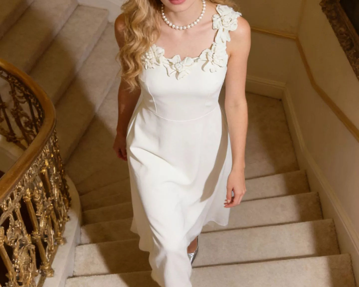 NEWYORKLISTED STYLE COLLECTION: Woman in a white dress with floral details walking down a staircase.