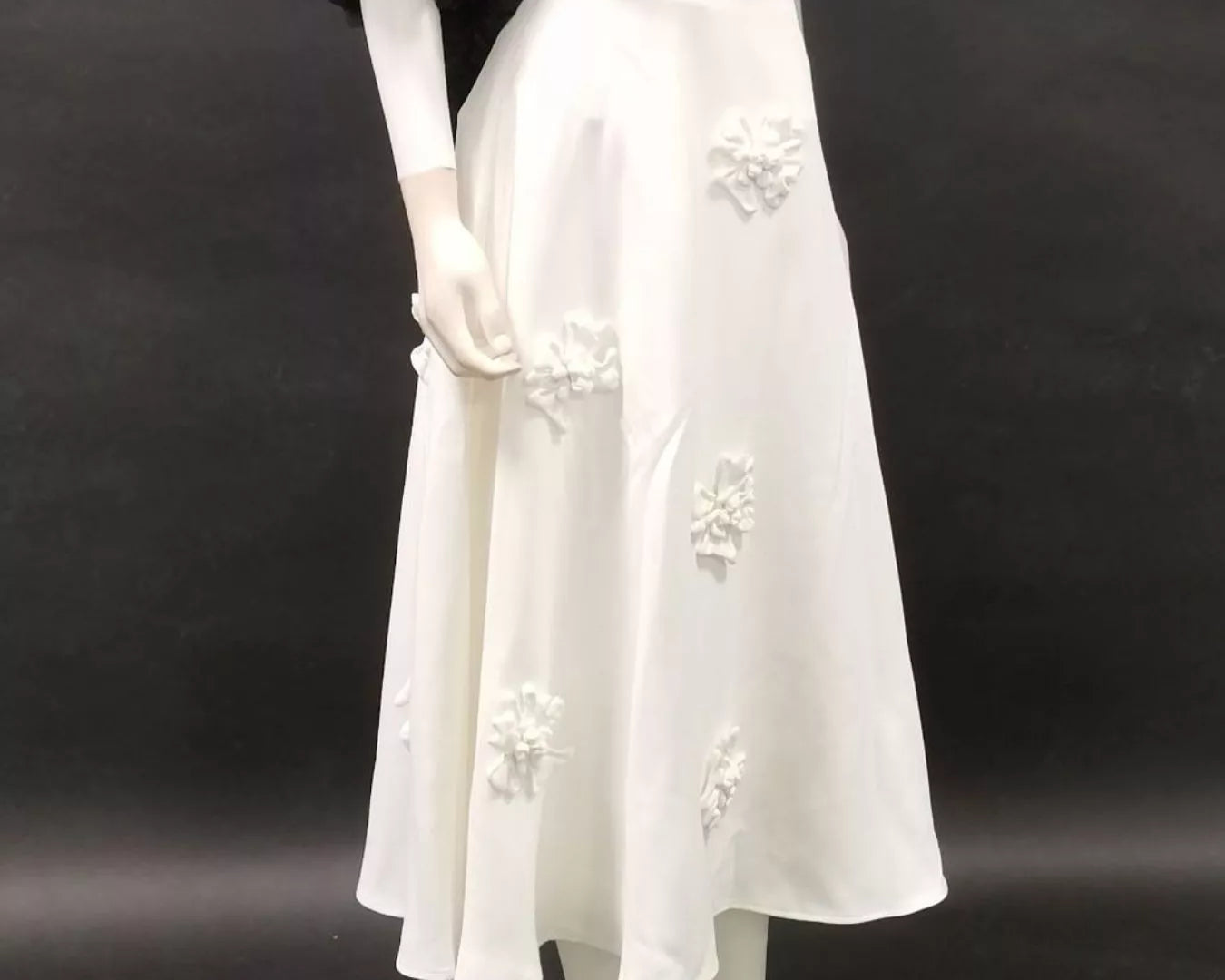 NEWYORKLISTED STYLE COLLECTION: Mannequin wearing a white dress with floral embroidery against a black background