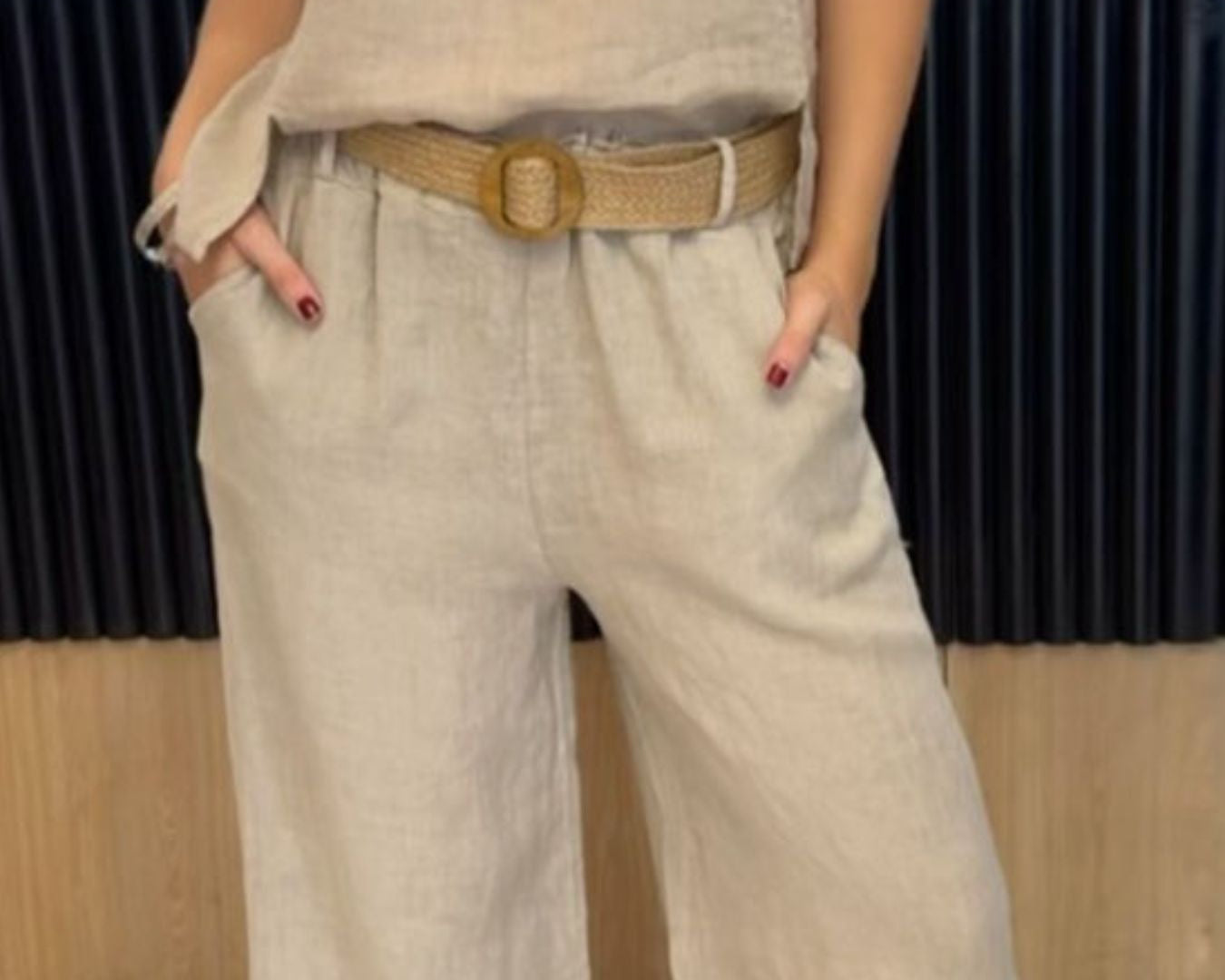 NEWYORKLISTED COMFORT COLLECTION: Person wearing a beige sleeveless top and wide-leg pants with a belt, standing indoors.