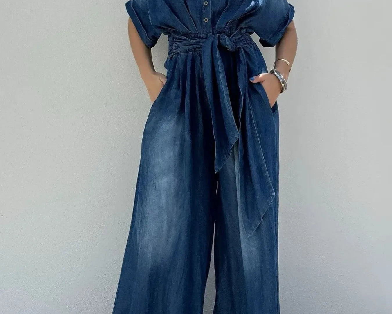 NEWYORKLISTED STYLE COLLECTION: Woman wearing a blue jumpsuit against a plain background