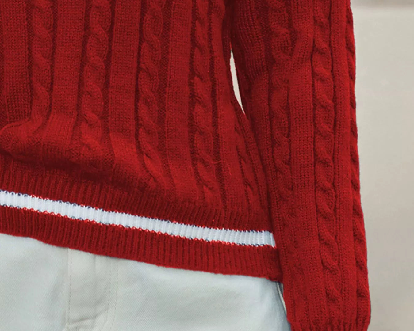 Red cable knit sweater with white stripes on a neutral background