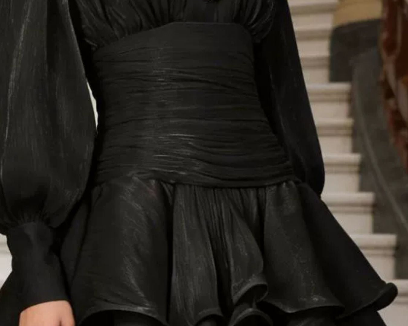 NEWYORKLISTED STYLE COLLECTION: Black dress with gold buttons worn by a person, standing on a staircase.