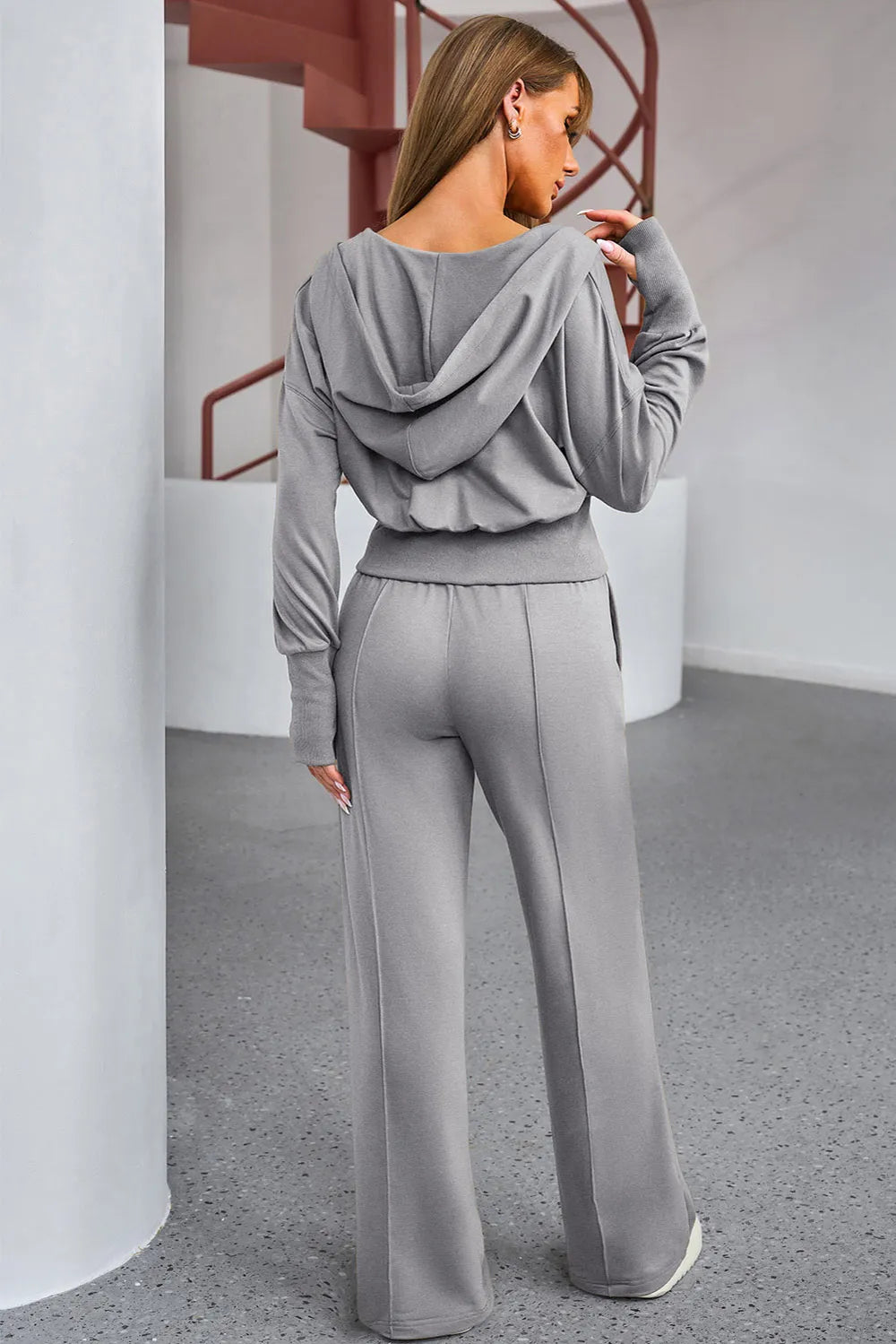 NEWYORKLISTED ACTIVEWEAR COLLECTION: Woman wearing a gray tracksuit in an indoor setting