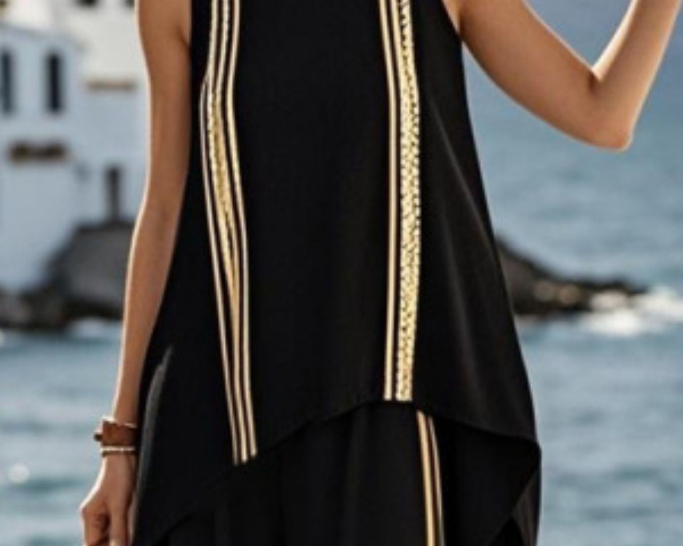 NEWYORKLISTED STYLE COLLECTION: Woman wearing a black sleeveless top with gold trim by the sea