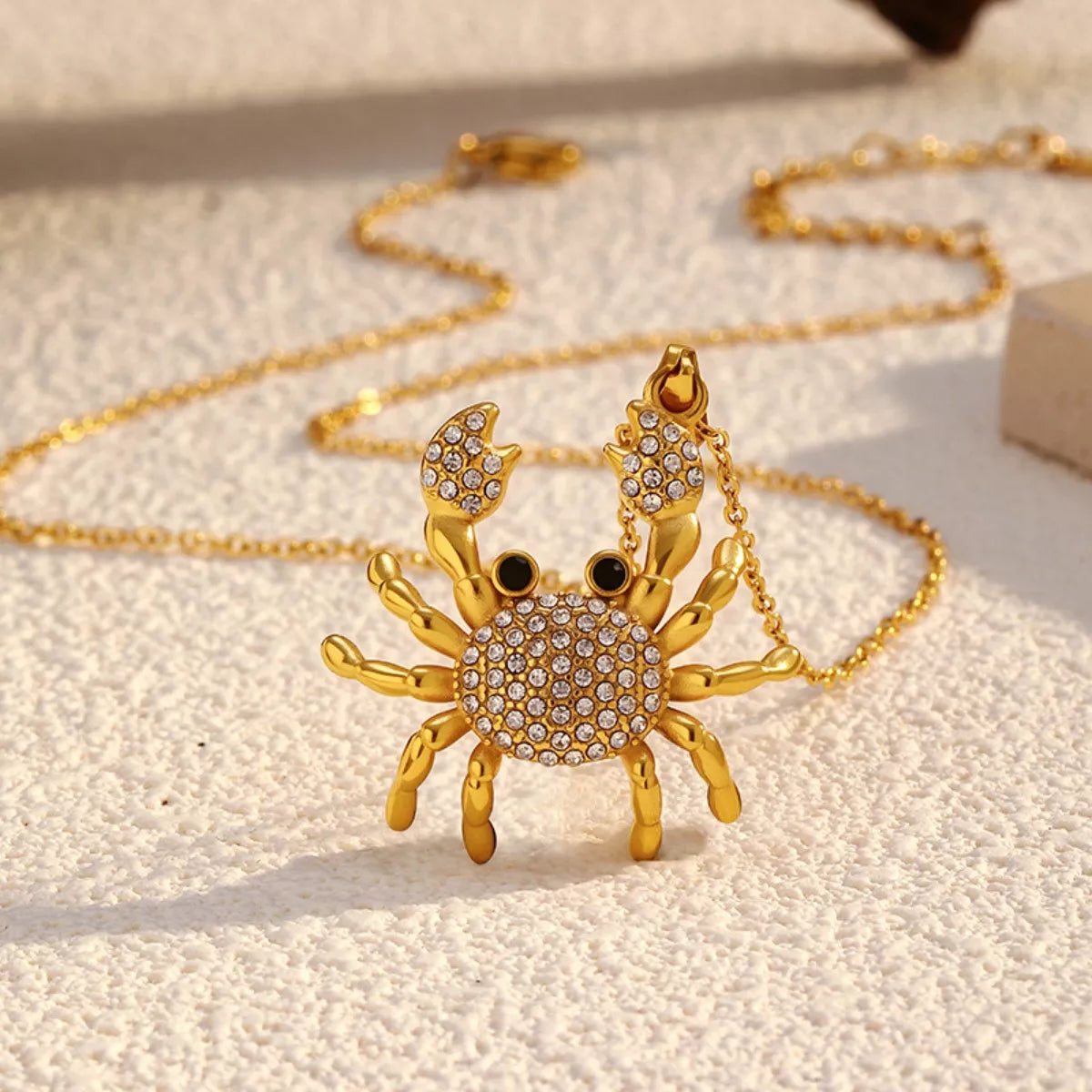 NYLD Glamour Collection by NEWYORKLISTED: Gold crab-shaped pendant necklace on a light background