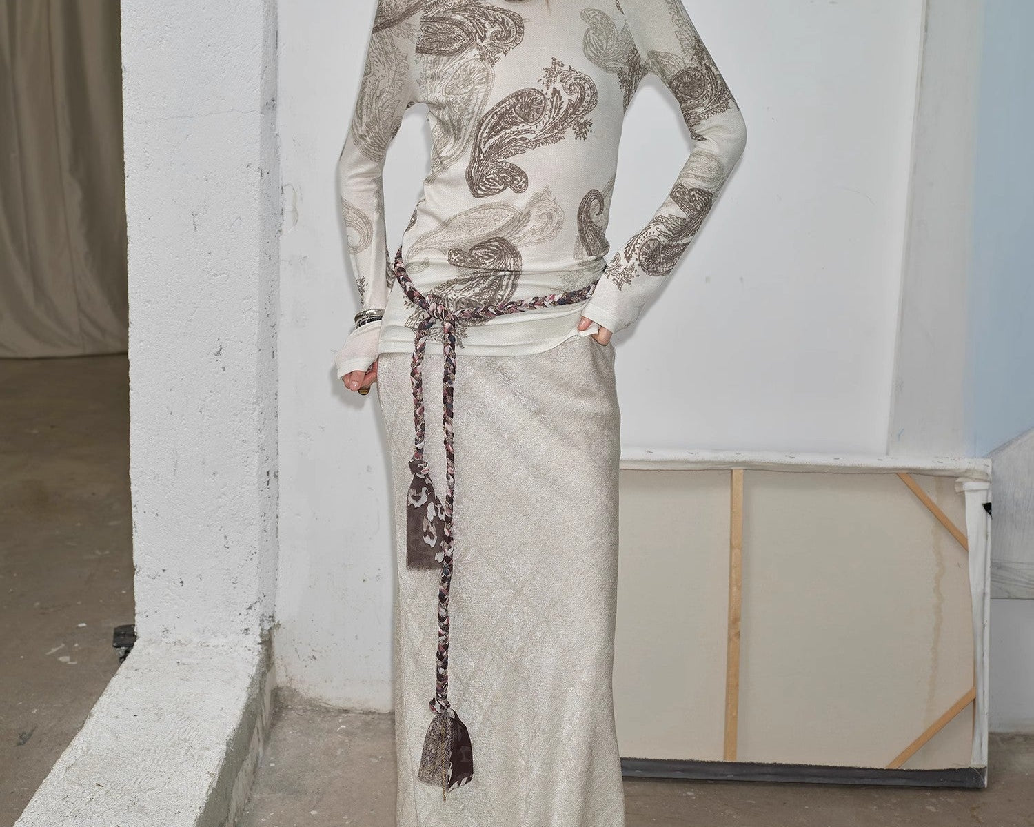 NEWYORKLISTED STYLE COLLECTION: Woman wearing a long, patterned dress standing against a plain wall.