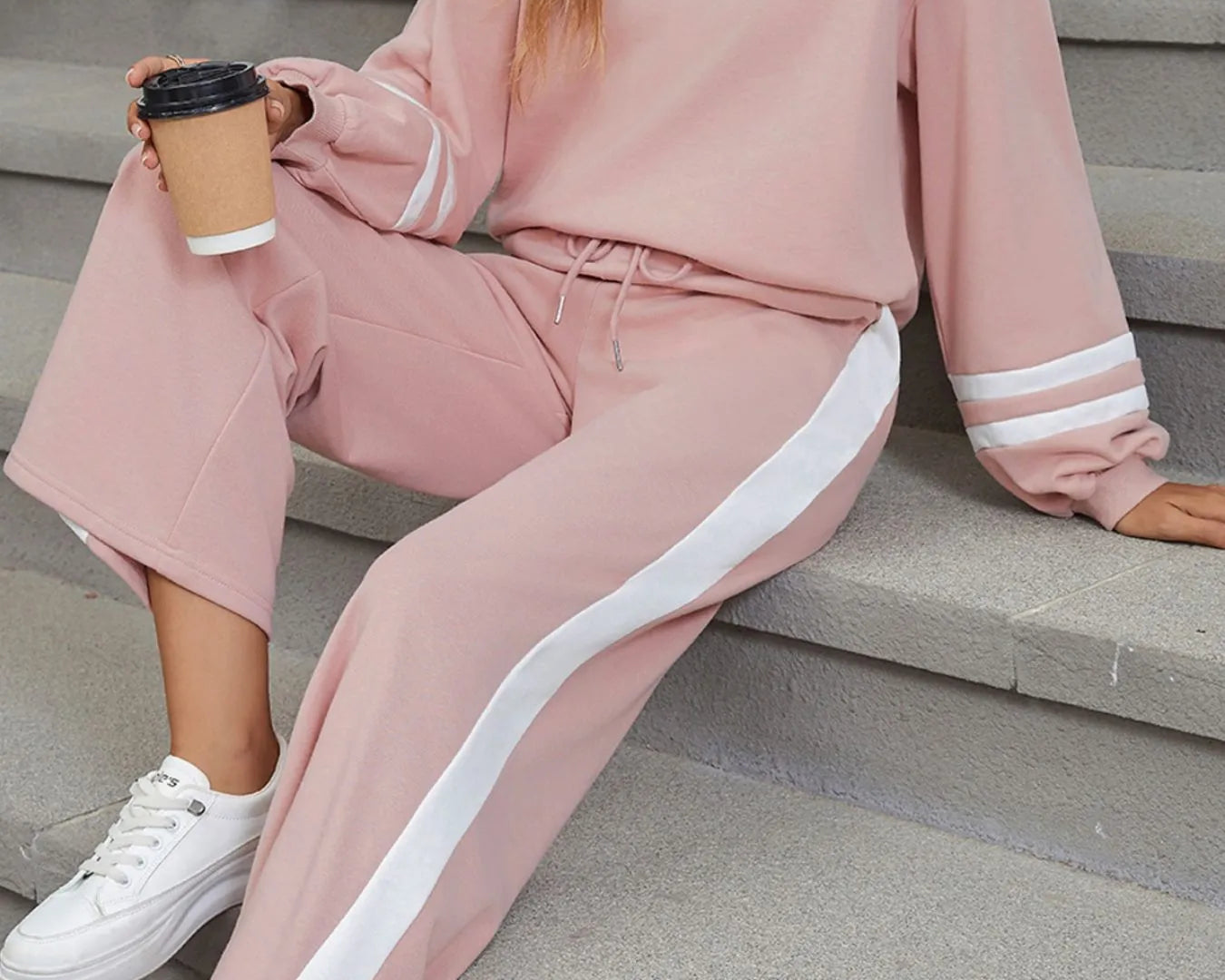 NEWYORKLISTED Comfort Collection: Person wearing a pink tracksuit with white stripes sitting on steps.