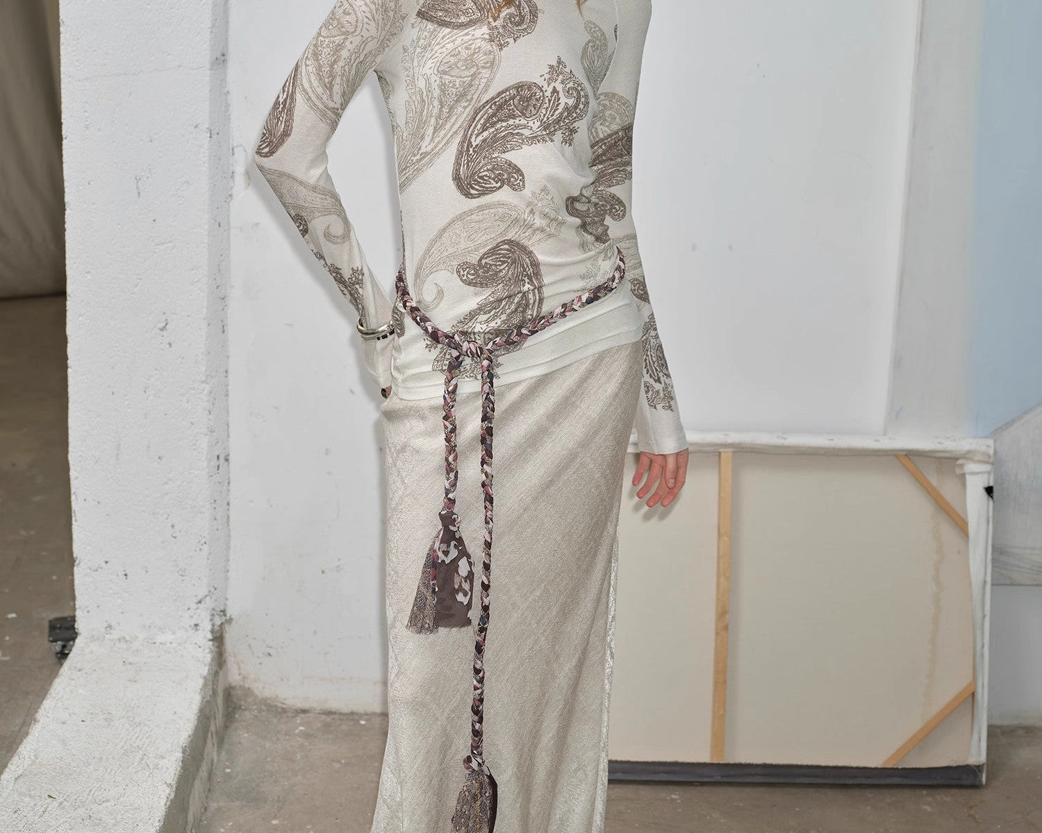 NEWYORKLISTED STYLE COLLECTION: Woman wearing a long, patterned dress with a white wall background