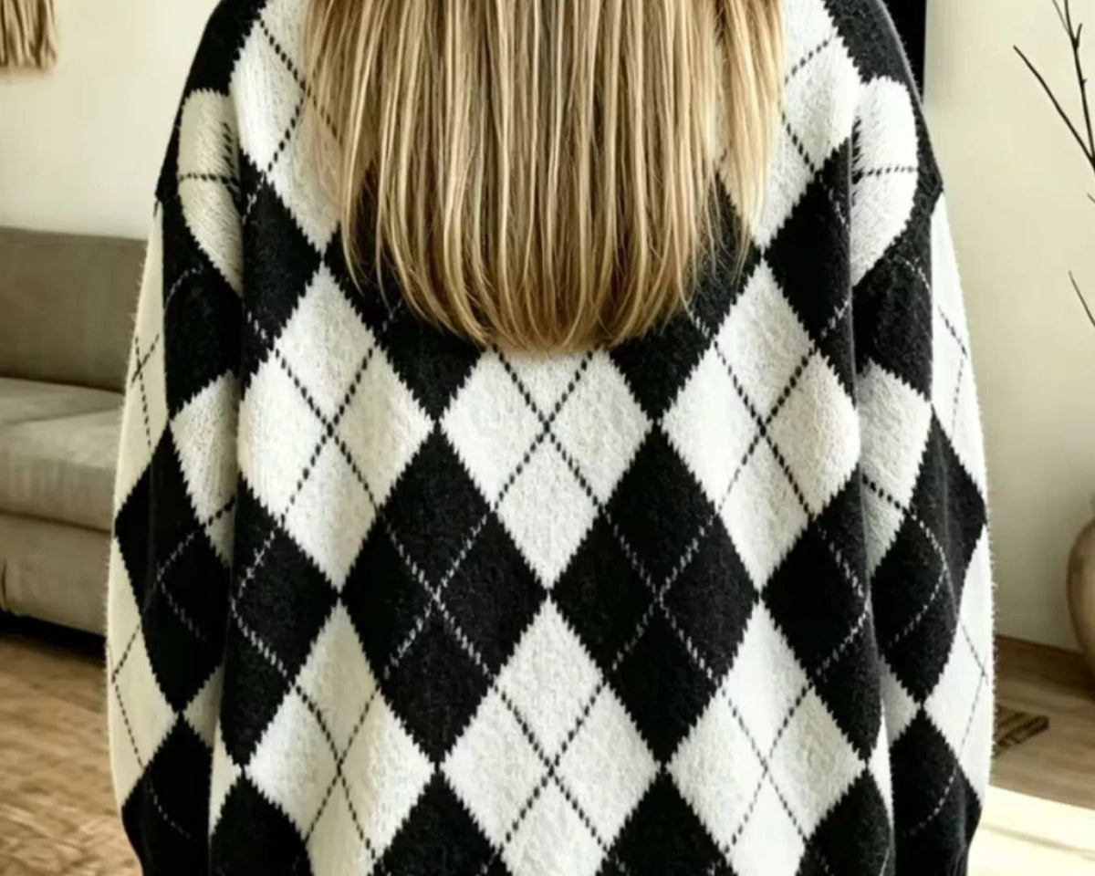 NEWYORKLISTED STYLE COLLECTION: A person viewed from behind wearing a black and white argyle knit sweater, paired with light blue jeans, in a brightly lit indoor room.