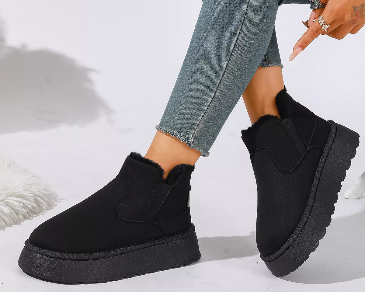NEWYORKLISTED SHOE COLLECTION: A person wearing black platform ankle boots with a fuzzy trim, paired with light blue skinny jeans, shown against a white studio background.
