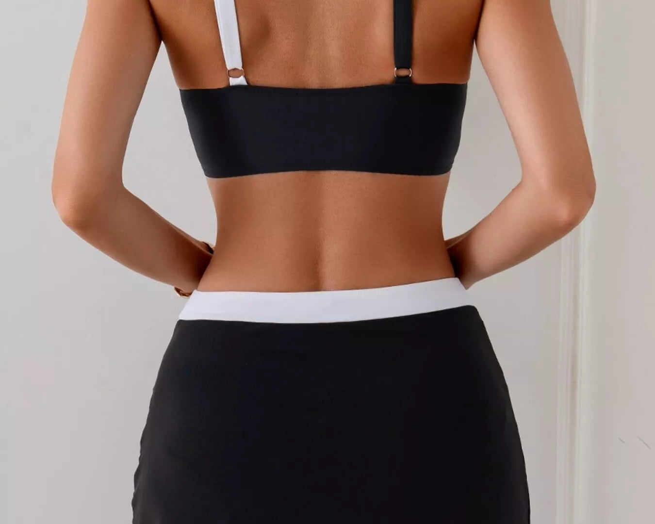NEWYORKLISTED EDEN COLLECTION: Person wearing a black bikini top and black skirt against a plain background