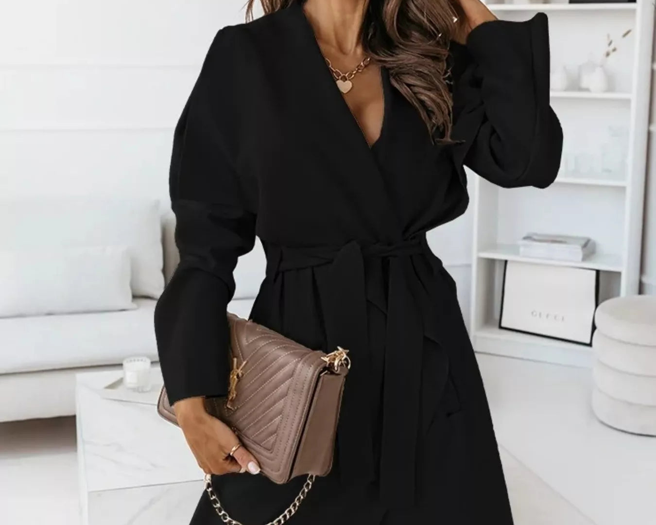 NEWYORKLISTED STYLE COLLECTION: Woman wearing a black coat and sunglasses in a modern living room.