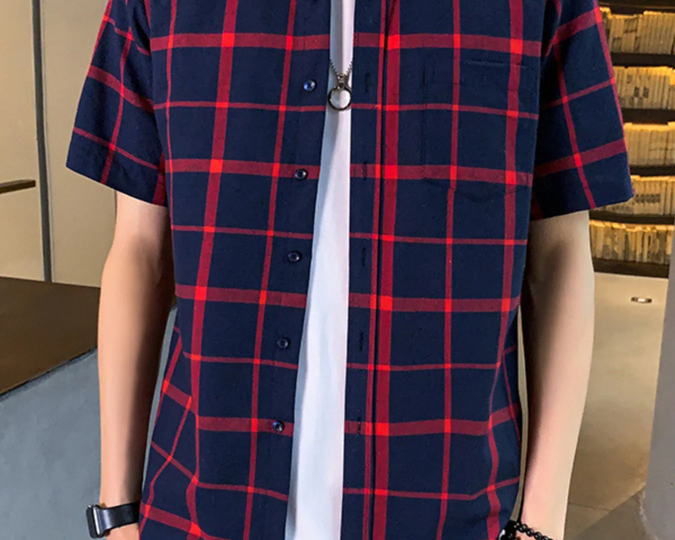Person wearing a blue and red plaid shirt over a white shirt.