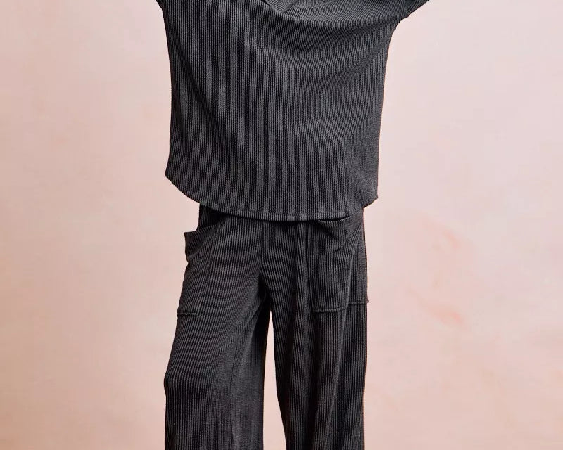 NEWYORKLISTED Comfort Collection: Person wearing a dark gray outfit with wide-legged pants against a plain background