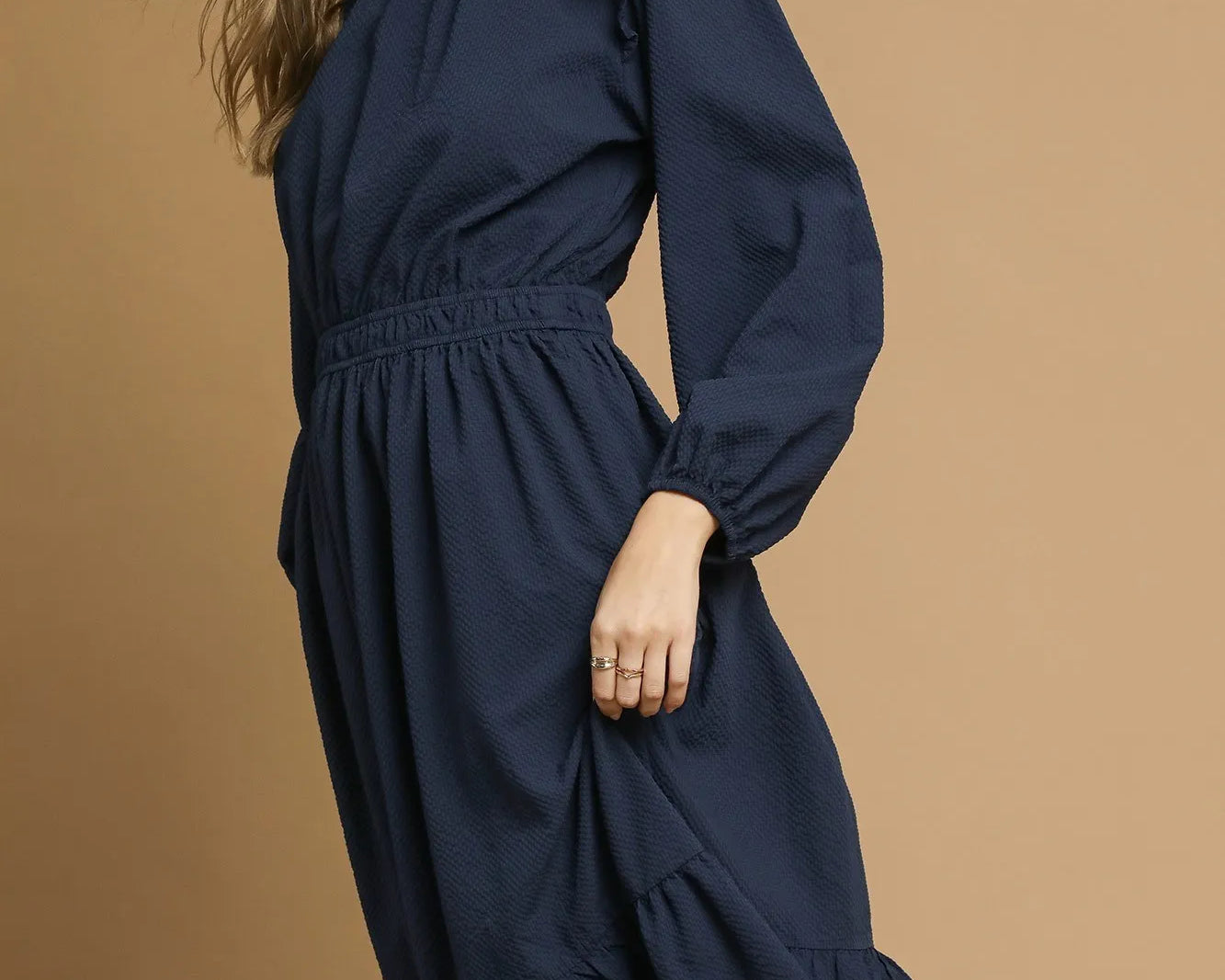 NEWYORKLISTED STYLE COLLECTION: Woman wearing a navy dress against a brown background