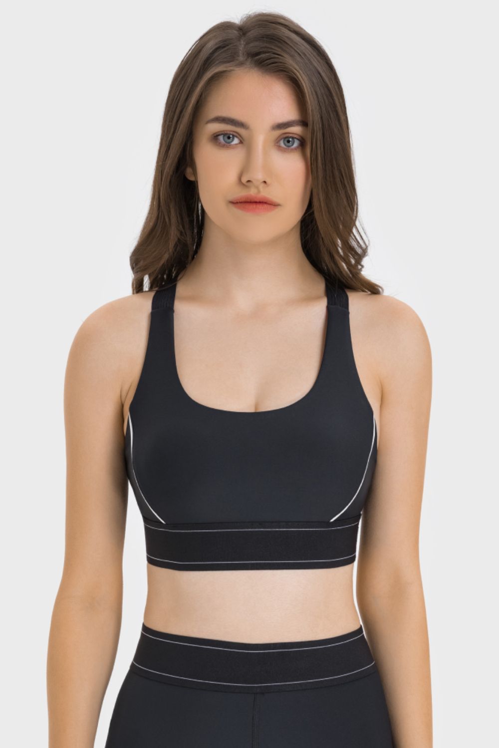 NEWYORKLISTED ACTIVEWEAR COLLECTION: Woman wearing a black sports bra and leggings on a white background