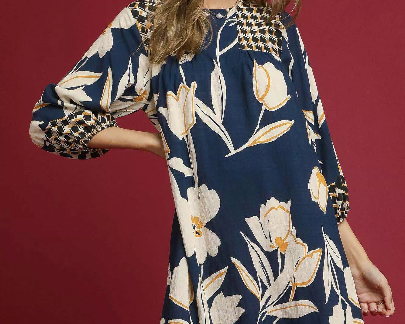 NEWYORKLISTED STYLE COLLECTION: Woman wearing a floral dress with long sleeves on a red background